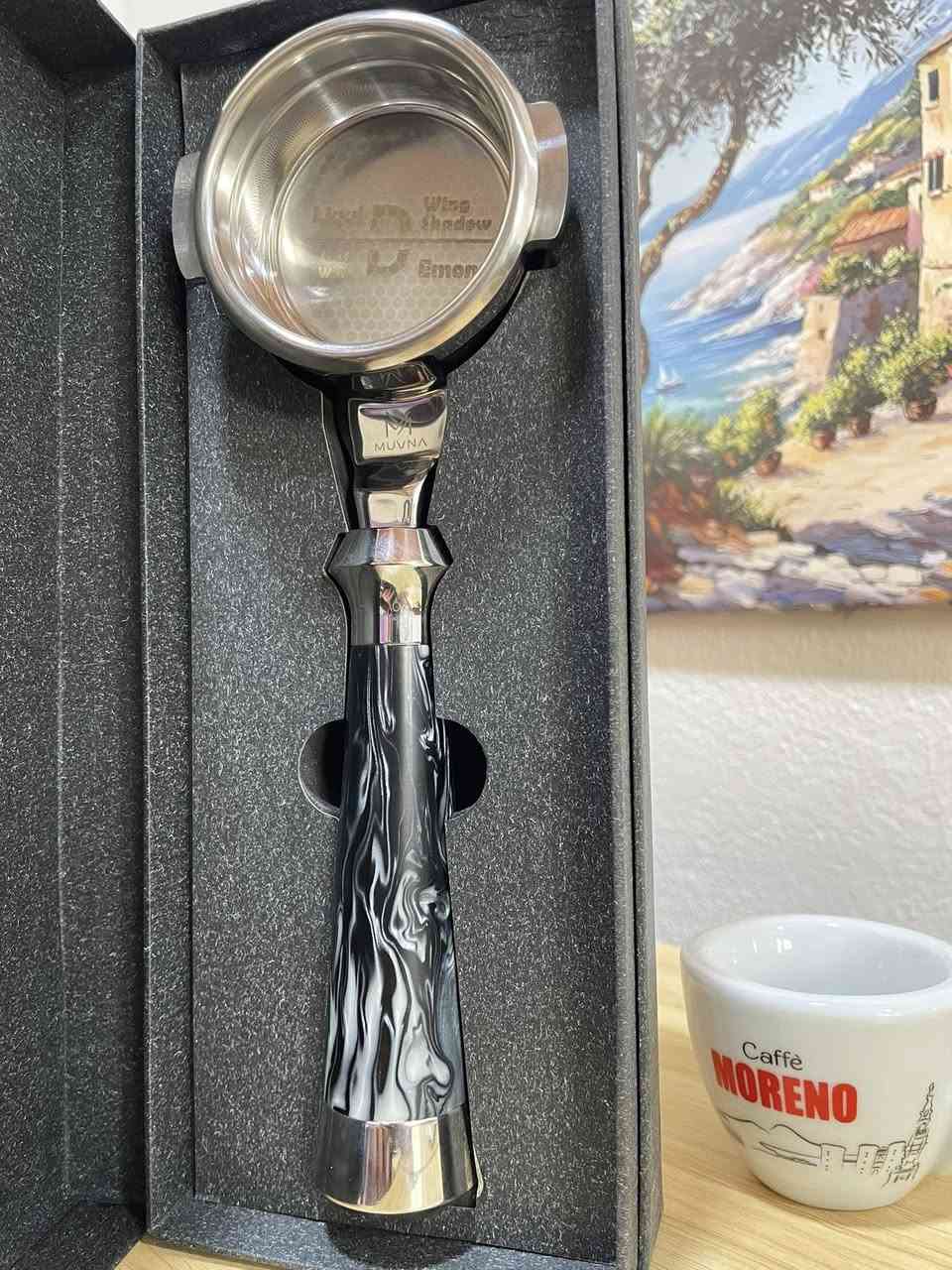 (Bottomless Portafilter) مخصص لآلات الإسبريسو الاحترافية، وهو من إنتاج شركة MUVNA المعروفة في أكسسوارات القهوة المختصة.

إليك تفاصيل ومواصفات هذه القطعة بناءً على الصور:
1. التصميم والمظهر
 المقبض (Handle): يأتي بتصميم مميز جداً بنقشة رخامية متموجة باللونين الأسود والأبيض (Resin/Acrylic swirl)، مع نهايات معدنية مصقولة من الكروم اللامع تعطي ثقلاً وتوازناً أثناء الاستخدام.

 الرأس (Head): مصنوع من المعدن المقاوم للصدأ (Stainless Steel) عالي الجودة والمصقول بعناية.
 العلامة التجارية: شعار MUVNA محفور بوضوح على الجزء المعدني الواصل بين المقبض والرأس.

2. السلة (Basket) المرفقة
 البورتافلتر يأتي ومعه سلة ترشيح احترافية مدمجة.
 تسمى هذه السلة في هذا الإصدار بـ "Liquid Demon" أو "Wing Shadow" كما هو محفور في قاع السلة داخلياً.
 تتميز السلة بنمط ثقوب دقيق جداً (توزيع متناسق يشبه خلايا النحل في الأطراف)، وهو تصميم مخصص لتحسين التدفق (High-flow) لضمان استخلاص متساوٍ لكامل كعكة القهوة (Puck) واستخراج نكهات أكثر وضوحاً وقوام غني.


**إذا كنت صاحب هذا الإعلان وتريد حذفه لأي سبب، رجاءا أرسل رسالة إلى الدعم الفني**