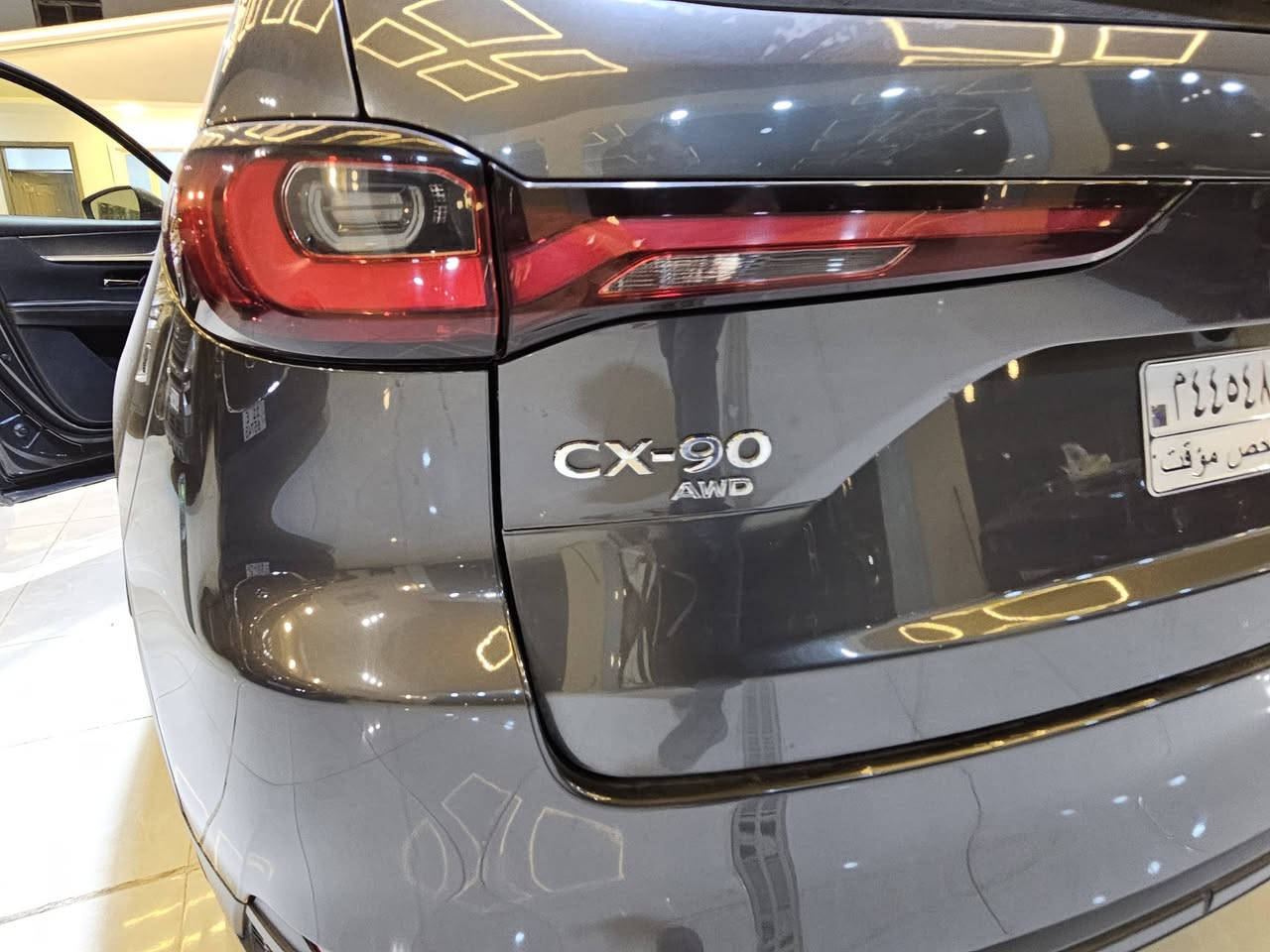 سيارة **مازدا CX-90 موديل 2024** بمحرك الـ 6 سلندر هجين (Mild Hybrid)  حيث تعتمد على محرك طولي ونظام دفع رباعي موجه للخلف لتحقيق أداء رياضي وفخم..
إليك أهم المواصفات التقنية والمميزات:
### 1. المحرك والأداء (e-Skyactiv G)
تتوفر بمحرك 6 أسطوانات متتالية (Inline-6) سعة 3.3 لتر مع شاحن تيربو، مدعوم بنظام هجين بسيط (48 فولت):
 * **القوة الحصانية:** تتوفر بخيارين حسب الفئة:
   * **الفئة القياسية:** 280 حصان وعزم دوران 450 نيوتن متر.
   * **الفئة العالية (S):** تصل إلى 340 حصان وعزم دوران 500 نيوتن متر (وهي أقوى سيارة إنتاجية من مازدا).
 * **ناقل الحركة:** أوتوماتيكي من 8 سرعات (جديد كلياً بدون محول عزم تقليدي لتوفير استجابة أسرع).
 * **نظام الدفع:** دفع كلي للعجلات (i-Activ AWD) بشكل قياسي.
 * **التسارع:** من 0 إلى 100 كم/ساعة في حوالي **5.8 إلى 6.5 ثانية** (حسب القوة).
### 2. استهلاك الوقود
 * تعتبر اقتصادية مقارنة بحجمها بفضل النظام الهجين، حيث تستهلك وسطياً حوالي **9.3 إلى 9.4 لتر لكل 100 كم**.
 * سعة خزان الوقود: **74 لتر**.
### 3. الأبعاد والمساحة
 * **الطول:** حوالي 5.1 متر، مما يجعلها سيارة SUV كبيرة بـ 3 صفوف من المقاعد.
 * **السعة:** تتوفر بخيارات 6 أو 7 أو 8 ركاب حسب التوزيع الداخلي.
 * **مساحة الأمتعة:** 608 لتر (خلف الصف الثالث) وتصل إلى 2025 لتر عند طي المقاعد.
### 4. التكنولوجيا والمقصورة الداخلية
 * **الشاشات:** شاشة مركزية كبيرة مقاس 12.3 بوصة تدعم Apple CarPlay و Android Auto لاسلكياً.
 * **النظام الصوتي:** يتوفر نظام Bose بـ 12 مكبر صوت في الفئات العليا.
 * **المواد:** استخدام جلود النابا، الأخشاب الطبيعية، وتطريزات مستوحاة من الفن الياباني التقليدي.
 * **ميزات إضافية:** فتحة سقف بانورامية، شاشة عرض على الزجاج الأمامي (Head-up Display)، وشحن لاسلكي.
### 5. أنظمة الأمان (i-Activsense)
 * نظام تثبيت السرعة التكيفي (الرادار).
 * نظام المساعدة في البقاء في المسار وتنبيه الخروج منه.
 * مكابح الطوارئ التلقائية مع رصد المشاة.
 * كاميرات 360 درجة مع خاصية "See-Through" لرؤية ما تحت السيارة أو حولها بوضوح.

**ملاحظة للمهتمين بالصيانة:** بما أنك تتابع تفاصيل المحركات بدقة، فإن هذا المحرك (Inline-6) مصمم ليكون متوازناً طبيعياً وأقل اهتزازاً من محركات الـ V6، وهو ما يعطي سلاسة تشبه محركات السيارات الألمانية الفاخرة.
ضررها  كفاله عامه تقرير مياه امطار تعمل وتسير
عداد المسافات ٤٠٠٠
للاستفسار معرض بلاتينيوم لتجارة السيارات  سامراء 
للاستفسار ***********
سيارة **مازدا CX-90 موديل 2024** بمحرك الـ 6 سلندر هجين (Mild Hybrid)  حيث تعتمد على محرك طولي ونظام دفع رباعي موجه للخلف لتحقيق أداء رياضي وفخم..
