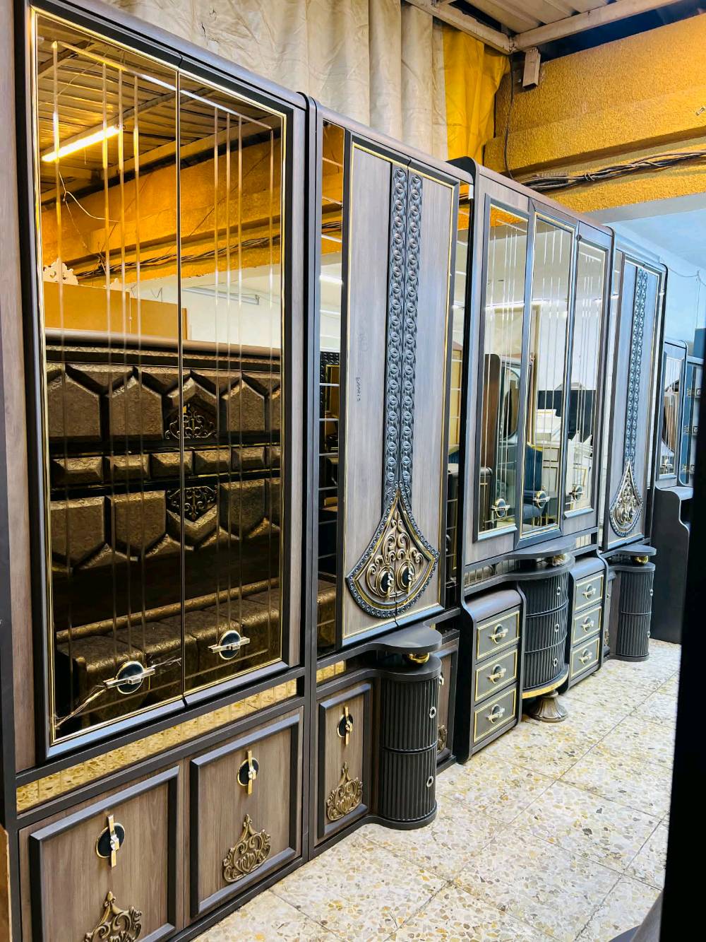 غرفة نوم مودرن وجديدة للبيع، تتميز بتصميم راقي وأنيق بلون رمادي مع لمسات ذهبية. تحتوي الغرفة على خزانة ملابس واسعة مع مرايا، وتسريحة مع أدراج ووحدات تخزين متعددة بالإضافة إلى طاولات جانبية بتصميم جمالي لتكمل الديكور. تناسب مختلف الأذواق وتضيف لمسة من الفخامة لأي منزل.