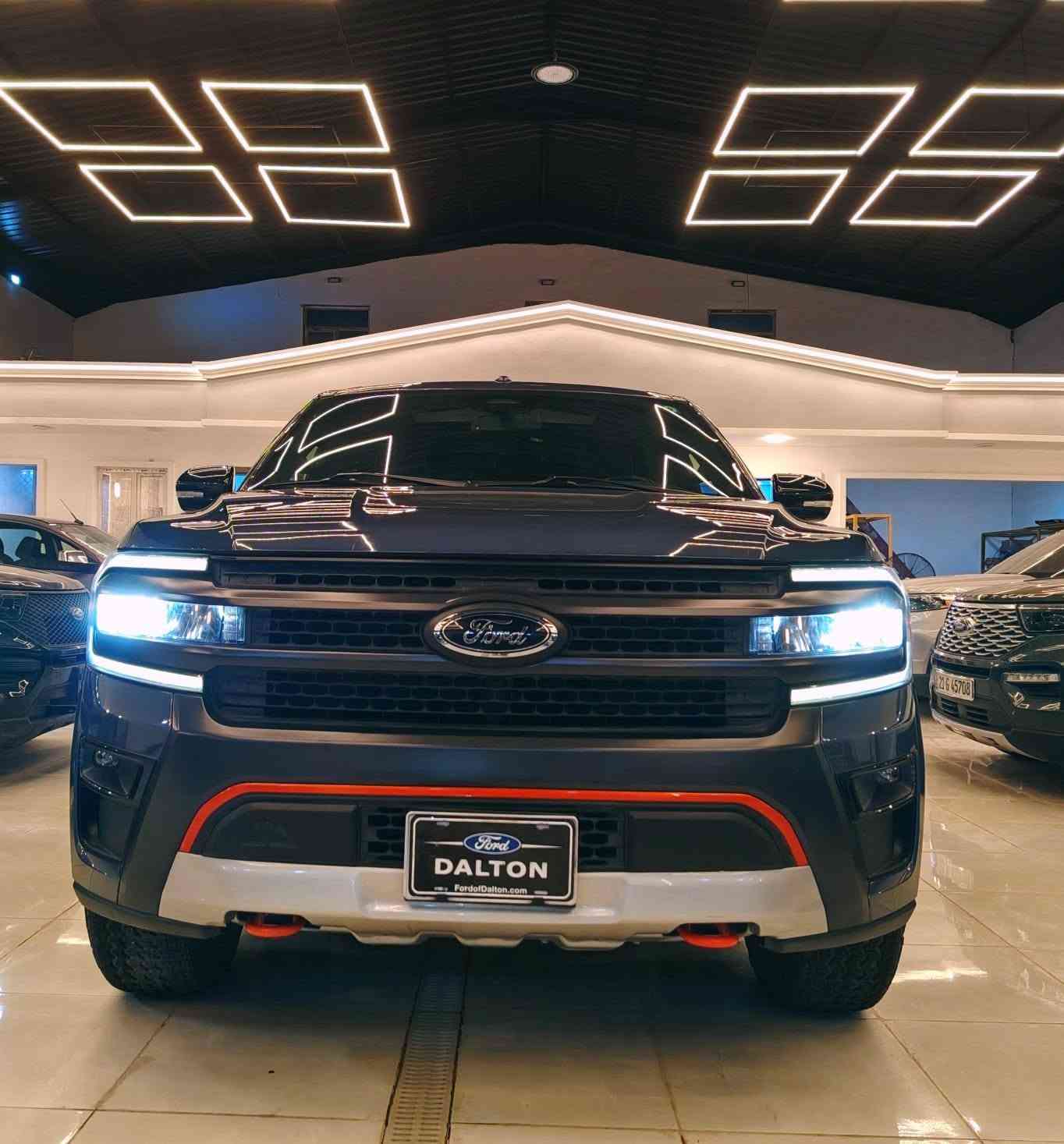 تعتبر فئة تيمبرلاين (Timberline) هي النسخة المخصصة للطرق الوعرة (Off-Road) من فورد إكسبدشن، وتتميز بمزيج بين القوة الهائلة للمحرك والجهوزية العالية للتضاريس الصعبة.
من معرض بلاتينيوم لتجارة السيارات اقدم لكم تحفة خليجيه وكالة القاصد تحت الضمان
فورد اكسبديشن ٢٠٢٣ البترة بسعر مغري
مغلفه ppf 
ممشى ٣٩٠٠٠ فئة تمبر لاين اوف رود من النسخ النادرة 
​المحرك: 6 سلندر (V6) سعة 3.5 لتر ذو شاحن توربيني مزدوج (EcoBoost)، وهو من فئة High-Output عالية الأداء.
​القوة والعزم: يولد قوة 440 حصان وعزم دوران 705 نيوتن متر (أقوى من الفئات القياسية).
​ناقل الحركة: أوتوماتيكي من 10 سرعات (SelectShift).
​نظام الدفع: دفع رباعي (4WD) مع علبة تحويل بسرعتين (دبل خفيف وثقيل) ونظام تفاضل خلفي إلكتروني محدود الانزلاق (eLSD).
​التجهيزات الخاصة بالطرق الوعرة
​الارتفاع عن الأرض: نظام تعليق مرتفع وخاص بالطرق الوعرة يمنح السيارة خلوصاً أرضياً مميزاً (حوالي 10.6 إنش).
​الإطارات والعجلات: جنوط ألمنيوم قياس 18 إنش بلون أسود داكن (Ebony Black)، مجهزة بإطارات "جودير رانجلر" مقاس 33 إنش مخصصة لجميع التضاريس.
​الحماية السفلية: ألواح حماية سفلية (Skid Plates) متينة مستوحاة من فورد رابتر لحماية المحرك وأجزاء السيارة السفلى. فولاذ
​الأنظمة المساعدة: نظام إدارة التضاريس بـ 7 وضعيات قيادة، ونظام Trail Turn Assist للمساعدة في الالتفاف الضيق بالبر.
​التصميم الخارجي والداخلي
​اللمسات الخارجية: تتميز بشبك أمامي أسود فريد، وهوك سحب بلون برتقالي مميز (Active Orange)، مع إضاءة LED كاملة.
​المقصورة: تتسع لـ 7 أو 8 ركاب، وتأتي بمقاعد جلدية (أو مخمل فاخر مخصص) مع تطريزات باللون البرتقالي.
​التبريد (مهم للخليجي): مكيف هواء أوتوماتيكي ثلاثي المناطق عالي الكفاءة يغطي الصفوف الثلاثة، بالإضافة إلى توفر ثلاجة وسيطة في الكونسول الوسطي.
​التقنيات والأمان
​الشاشات: شاشة ترفيه وسطية ضخمة تعمل باللمس قياس 12 إنش (أو 15.5 إنش في الفئات الأعلى الفاخرة) بنظام SYNC 4، مع شاشة عدادات رقمية بالكامل.
​النظام الصوتي: نظام فاخر من Bang & Olufsen (B&O).
​السلامة: نظام كشف النقاط العمياء مع دعم المقطورة، رادار ومثبت سرعة متكيف، كاميرات محيطية 360 درجة، ونظام المحافظة على المسار.
تعتبر فئة تيمبرلاين (Timberline) هي النسخة المخصصة للطرق الوعرة (Off-Road) من فورد إكسبدشن، وتتميز بمزيج بين القوة الهائلة للمحرك والجهوزية العالية للتضاريس الصعبة.
بصمه وتشغيل عن بعد 
كشنات ميموري
١٢ منفذ شحن ٨ راكب 
للاستفسار 
*********** سيف الحسني
لمعرفة السعر اكتب تم
