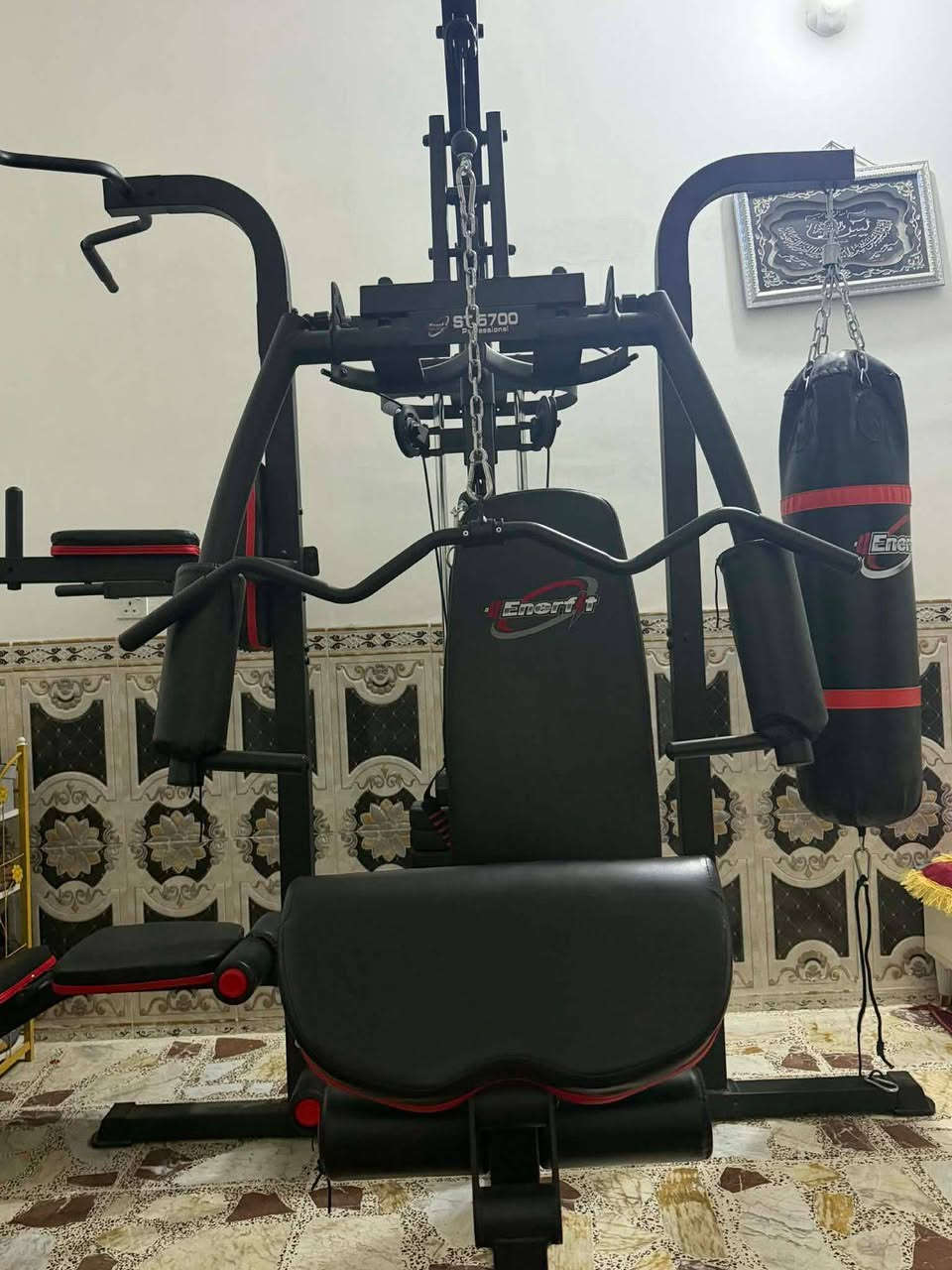 السلام عليكم ورحمة الله
مكلف بالنشر
جهاز رياضي متعدد الاستعمالات الرياضيه

Multi Gym 

Home Gym Machine
أي جهاز النادي المنزلي لأنه يجمع عدة أجهزة في جهاز واحد.

وهو جهاز جيم منزلي متعدد التمارين.
العلامة الظاهرة عليه هي Enerfit، وغالباً هذا النوع يأتي بعدة محطات تمارين في جهاز واحد.

التمارين التي يمكن عملها بهذا الجهاز:
تمرين الصدر (Chest Press)

تمرين سحب الظهر العلوي (Lat Pulldown)

تمرين الفراشة للصدر (Butterfly)

تمارين الذراعين (بايسبس وترايسبس)

تمارين الأرجل

تمارين البطن

الأجزاء الظاهرة في الصورة:
مقعد التمرين

أذرع الفراشة للصدر

شفت السحب العلوي

بكرات مع أوزان

أسطوانة تمارين الأرجل

كيس ملاكمة جانبي ضخم جدا 

✅ هذا الجهاز يعتبر نادي رياضي كامل في البيت لأنه يسمح بعمل أغلب تمارين الجسم
المساحه التي يتطلبها الجهاز ٣ متر في ٣ متر 

السعر المطلوب ٧٠٠ الف
الجهاز بحاله الوكاله نظافه ١٠٠ بالمئة
مكانه الجهاز الفلوجه حي الجغيفي الثانيه
للاستفسار
***********
***********
***********
