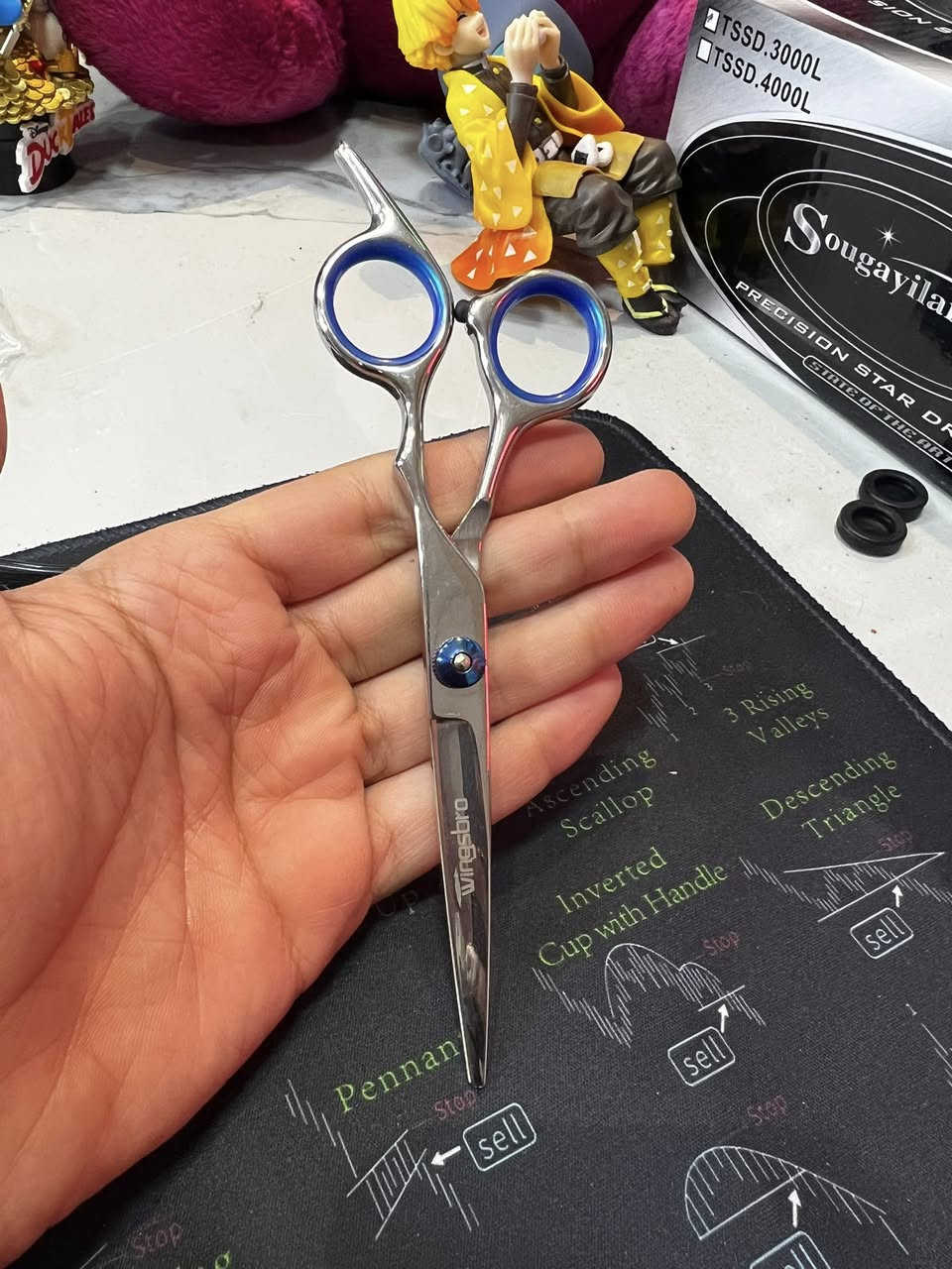 مقص حلاقة  (Straight Scissors): هذا المقص الأساسي، حاد ومصمم حتى يكص الشعر بدقة. بي "ساندة" للأصبع حتى تسيطر عليه وما يتعب إيدك.
• مقص تشفير (Thinning Scissors): هذا المقص اللي بي سنون (مثل المشط). وظيفته يقلل كثافة الشعر (يخففه) بدون ما يكصر طوله، ويستخدموه حتى يدمجون طبقات الشعر ويطلع الموديل مرتب.
• مشط حلاقة: مشط أسود كلاسيكي، جهة سنونها ناعمة وجهة خشنة، ضروري ويه الكص.
• ماشة (قرصات) شعر: ذني السود الثنين، يفيدنك حتى تعزل الشعر وتكص جزء جزء براحتك.
• وصلة تنظيف: قطعة قماش (لونها خردلي) ناعمة حتى تمسح بيها المقصات من الدهن أو بقايا الشعر وره ما تخلص.
• محفظة (قلمية): الجنطة السودة الصغيرة اللي تلم الغراض كلهن حتى لا يضيعن ولا يتثلم المقص.
ليش هذا السيت زين؟
1. الديزاين: المقصات بيها حلقات زرقة داخلية، هاي مطاطية (ربر) حتى لا تزلق أصابعك وتكون مريحة بالشغل.

السعر 65.000

الحجز ***********
