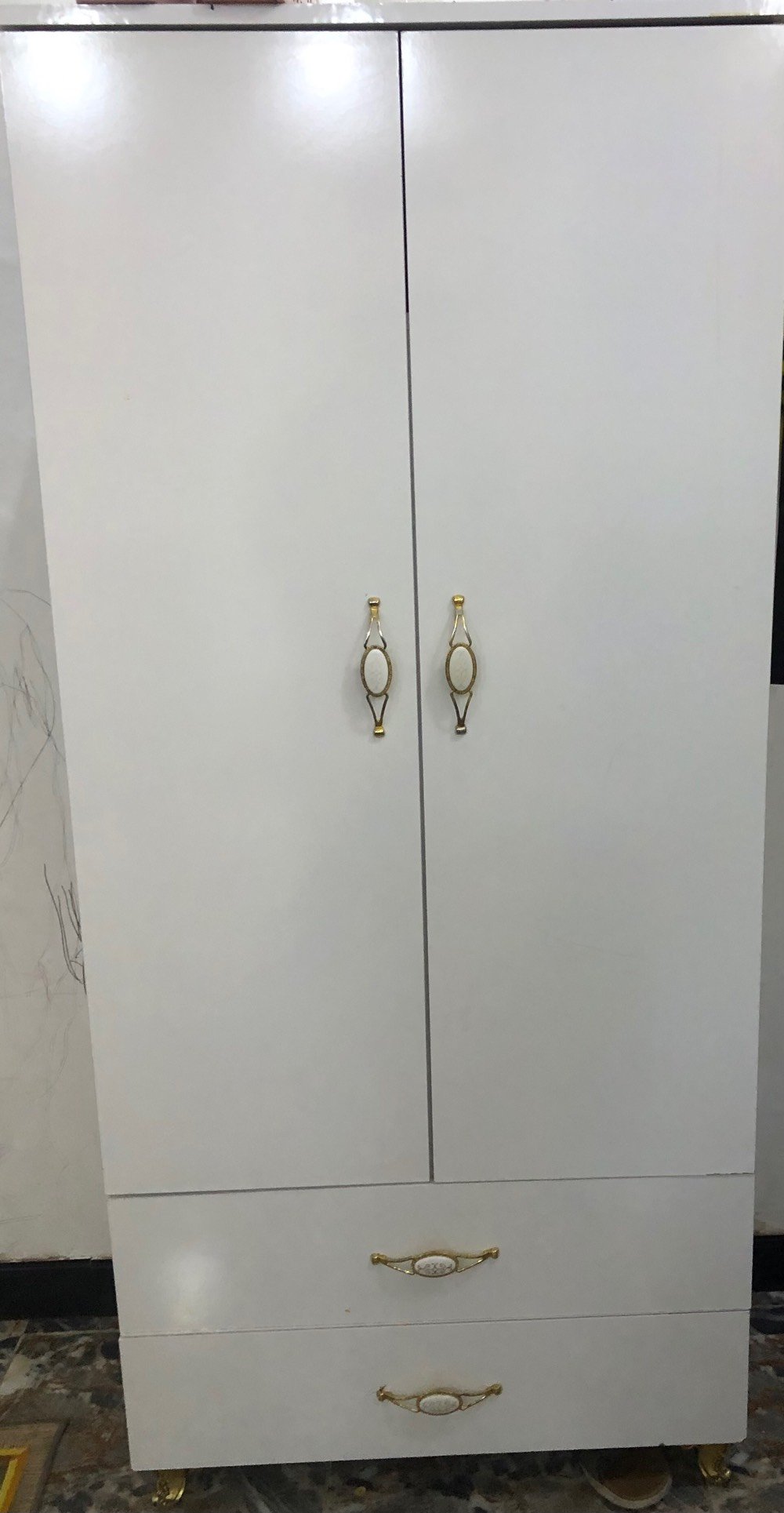 كنتور ملابس أبيض أنيق ومناسب للتخزين، يحتوي على قسم لتعليق الملابس ورفوف متعددة لتخزين مختلف الأغراض. الأبواب مزودة بمقابض ذهبية لإضافة لمسة من الفخامة. هذا الكنتور مثالي لغرفة النوم أو أي مكان يحتاج تنظيم إضافي.