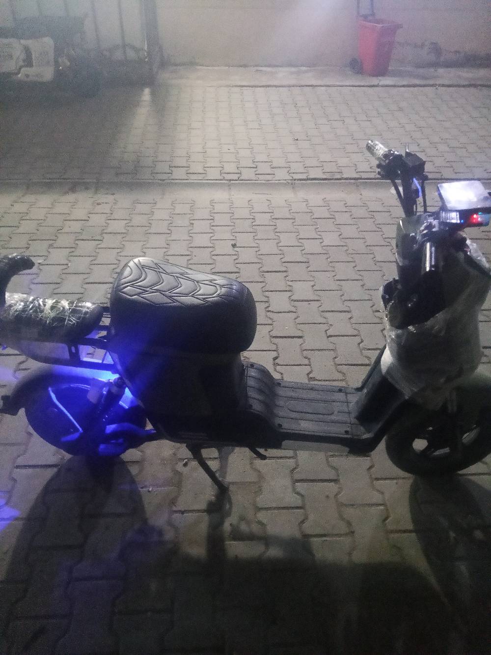 دراجة كهربائية حديثة، مزودة بأضواء ليد لإضاءة مميزة ليلاً. شاشة العرض توضح السرعة ومستوى البطارية. حالة الدراجة ممتازة وجديدة تماماً، مثالية للتنقل اليومي الاقتصادي والسريع داخل المدينة.