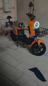 دراجة كهربائية جديدة وغير مستعملة، لون برتقالي مميز وضوء أمامي قوي. مث...