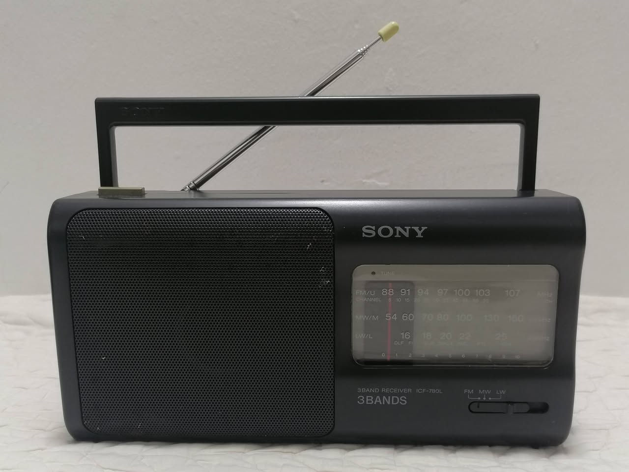 هذا الجهاز هو راديو محمول من شركة سوني (Sony)، وتحديداً الموديل ICF-780L.
المواصفات الأساسية:
نطاقات البث: يدعم 3 موجات راديو هي FM و MW و LW.
مصدر الطاقة: يعمل بالكهرباء المباشرة (كابل سلكي) أو عن طريق البطاريات (عادةً 4 بطاريات قلم من نوع AA).
التصميم: يتميز بتصميم كلاسيكي مع مقبض علوي للحمل وهوائي (Antenna) قابل للسحب.
بلد الصنع: تم تصنيع هذا الموديل في اليابان. 
يُعتبر هذا الجهاز من القطع "الفينتج" أو الكلاسيكية التي تعود لفترة التسعينيات، وهو معروف بنقاء الصوت ودقة الاستقبال.
العنوان بغداد - البياع موجود ***********‪ واتساب
