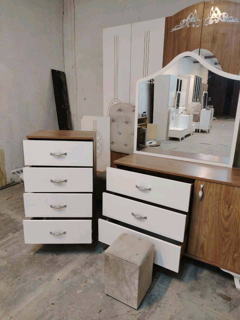 مجموعة غرفة نوم جديدة تحتوي على خزانات واسعة ومرآة وطاولة زينة مصنوعة من خشب متين. التصميم يجمع بين الأناقة والخطوط العصرية مع لمسات كلاسيكية. مثالية لإضفاء لمسة جمالية على غرفة النوم.