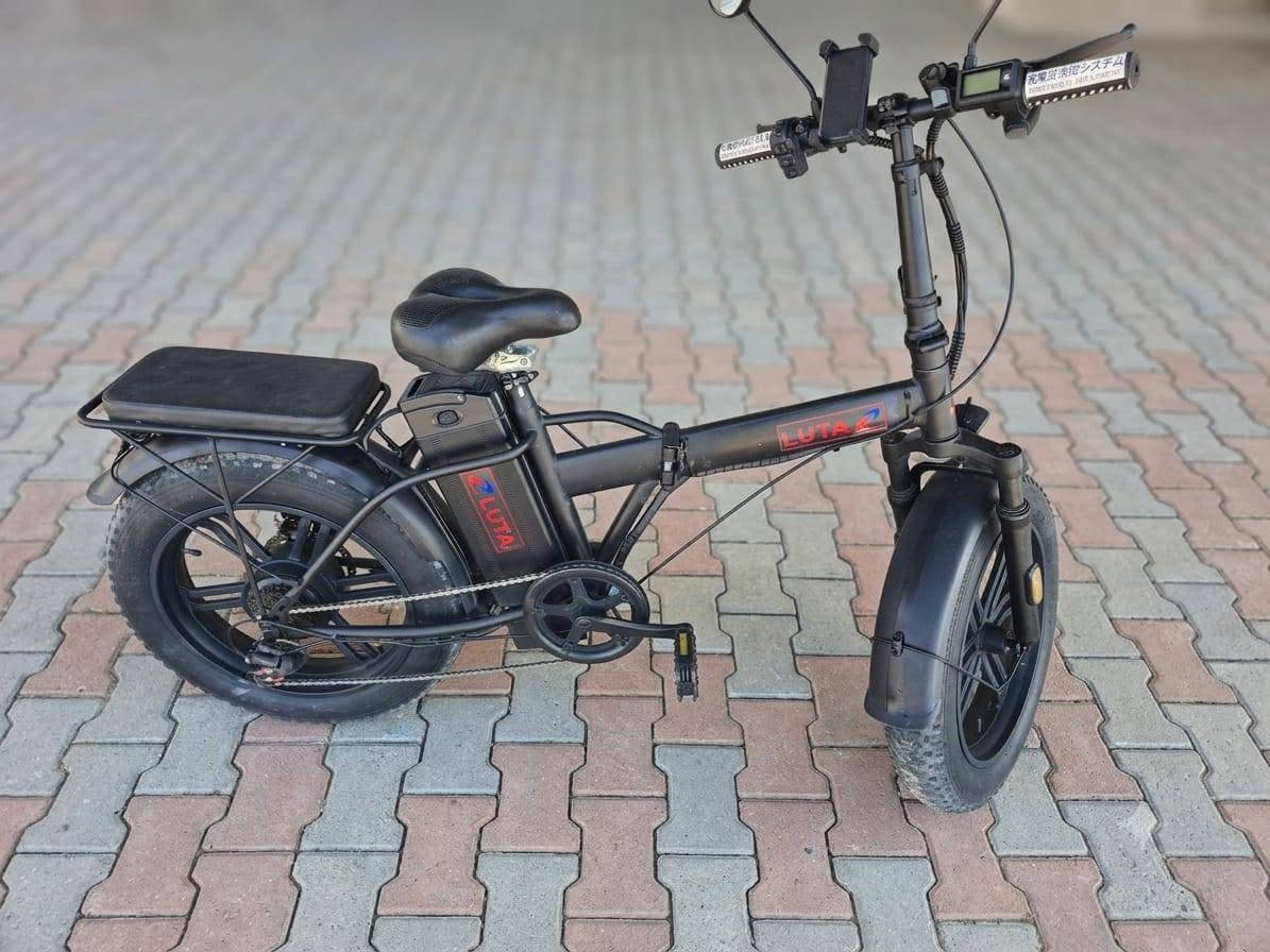هذه الدراجة الظاهرة في الصورة هي دراجة كهربائية عريضة الإطارات وقابلة للطي (Folding Fat-Tire E-Bike) من العلامة التجارية LUTA (لوتا).
تتميز هذه الفئة من الدراجات بالعملية والقدرة على السير في الطرق الوعرة واليومية بفضل تصميمها المتين. إليك المواصفات التفصيلية للدراجة بناءً على تصميمها ومكوناتها الظاهرة:
​1. الهيكل والتصميم (Frame & Design)
​قابلية للطي: الدراجة تحتوي على قفل مفصلي في منتصف الهيكل، بالإضافة إلى إمكانية طي عمود المقود (الستيرن)، مما يسهل شحنها أو وضعها في صندوق السيارة.
​اللون: تأتي بلون أسود مطفي (Matte Black) مع شعار العلامة التجارية LUTA باللون الأحمر والأزرق.
​المقعد الخلفي: مزودة برف خلفي مدمج يحتوي على وسادة سميكة ومريحة (مسند مخصص لركوب شخص آخر أو لتثبيت الأغراض).
​المقعد الرئيسي: مقعد عريض ومريح ومبطن بشكل جيد لامتصاص الصدمات أثناء القيادة لمسافات طويلة، مع إمكانية تعديل الارتفاع.
​2. الإطارات والمساعدات (Wheels & Suspension)
​نوع الإطارات: إطارات عريضة جداً من نوع (Fat Tires) مخصصة لجميع التضاريس (الرمل، الحصى، الطرق الوعرة، والأسفلت) تمنح الدراجة ثباتاً ممتازاً.
​الجنوط: جنوط رياضية صلبة مصنوعة من الألمنيوم (شفرات/مراوح) وليست سيم (أسلاك)، وهي أكثر متانة وأقل حاجة للصيانة.
​المساعدات: تحتوي على مساعدات أمامية (Front Suspension Fork) لامتصاص الصدمات واهتزازات الطريق لضمان قيادة سلسة.
​مصدات الطين: رفارف (فندرات) أمامية وخلفية كاملة لحماية الراكب من رذاذ الماء أو الطين.
​3. النظام الكهربائي والميكانيكي (Electric & Mechanical System)
​المحرك: محرك كهربائي خلفي (Rear Hub Motor) مدمج في عجلة الدراجة الخلفية، (عادة في هذه الفئات تتراوح قوته بين 350 واط إلى 500 واط).
​البطارية: تقع في الصندوق المخصص أسفل المقعد مباشرة وفوق الدواسات، وهي محمية وقابلة للإزالة للشحن المنفصل بواسطة مفتاح أمان.
​نظام الكبح (الفرامل): مكابح قرصية (Disc Brakes) أمامية وخلفية لتوفير قوة كبح ممتازة واستجابة سريعة في مختلف الظروف الجوية.
​الدواسات: دواسات ميكانيكية عادية تتيح لك قيادة الدراجة كدراجة هوائية طبيعية في حال نفاد الشحن، أو استخدام نظام المساعدة

 على التبديل.

     لــلــبـيـع 《《《《《《 السعر 700 الف
ابوغريب عمارة الوزة.    ***********

هذه الدراجة الظاهرة في الصورة هي دراجة
 كهربائية عريضة الإطارات وقابلة للطي (Folding Fat-Tire E-Bike) من العلامة التجارية LUTA (لوتا).
