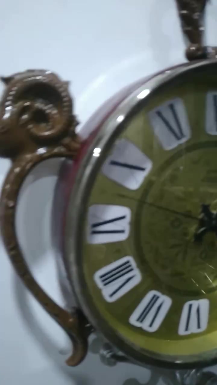 ساعة حائط مميزة جداً وتحمل طابعاً كلاسيكياً عتيقاً (Vintage/Retro)، وتحديداً من الساعات التي اشتهرت بها شركة "ريذم" (Rhythm) أو "كاسيو" (Casio) اليابانية في فترة السبعينيات والثمانينيات، والتي كانت تعتمد على تصاميم وزخارف بلاستيكية أو معدنية تحاكي الأنماط الأوروبية الكلاسيكية الكثيفة. مواصفات 
​ التصميم والهيكل الخارجي (The Aesthetic)
​ التصميم مستوحى من شكل "ساعة الجيب الكلاسيكية العتيقة" من حيث وجود الحلقة العلوية الكبيرة والمقبض، ولكن تمت إضافة عناصر زخرفية بارزة تمنحها طابعاً ملكياً أو ريفياً أوروبياً (Baroque / Rococo Style).
​التماثيل والزخارف: * رأس الكبش (أو الوعل): نلاحظ وجود رأس كبش بقرون دائرية مميزة في أعلى الساعة باللون الفضي المحاط بإطار بني مزخرف، وتتكرر رؤوس الكباش على الجانبين الأيمن والأيسر كحوامل أو مقابض جانبية. هذا الرمز غالباً ما يرمز للقوة أو يرتبط بتصاميم الساعات الجدارية المخصصة لغرف الضيوف أو المكاتب الفخمة.
​القاعدة السفلية: مزينة بزخرفة معدنية ملتوية باللون الفضي (Scrollwork) لتعطي توازناً بصرياً مع الجزء العلوي.
 الميناء والعقارب (The Dial & Hands)
​الخلفية (الميناء): تأتي باللون الأخضر الزيتوني المتدرج إلى الأصفر (Sunburst/Gradient Effect)، وهو لون كلاسيكي شهير جداً في حقبة السبعينيات. يوجد في منتصف الميناء نقوش وزخارف نباتية ناعمة ملتفة (Filigree Pattern).
​الأرقام: أرقام رومانية كبيرة باللون الأسود موضوعة داخل مربعات أو مخروطيات بيضاء بارزة، مما يسهل قراءتها ويمنح الميناء بُعداً ثلاثي الأبعاد.
​العقارب: العقارب مصممة على الطراز الكلاسيكي (Retro/Ornate Hands) مع وجود عقرب ثوانٍ نحيف.
​الكتابة: يظهر في النصف السفلي من الميناء كلمة "QUARTZ"، مما يؤكد أن الساعة تعمل بحركة الكوارتز الحديثة (التي تعتمد على البطارية) وليست حركة ميكانيكية بالزنبرك، وهو ما كان ثورة في دقة الوقت خلال تلك الحقبة.
 التحليل الفني والمنشأ
​الحركة الداخلية: تعمل الساعة بنظام الكوارتز (Battery-powered Quartz Movement)، وغالباً ما تكون الماكينة الداخلية يابانية الصنع (مثل ماكينات Rhythm الموثوقة جداً في امتصاص الطاقة وتعمير البطارية).
​المواد المستخدمة: الهيكل الخارجي مصنع من البلاستيك المقوى عالي الجودة (Hard Injection-Molded Plastic) الذي كان يُدهن بطبقات تحاكي الخشب الداكن أو النحاس والمعدن الفضي، وهي تقنية برعت فيها المصانع اليابانية لإنتاج ساعات حائط خفيفة الوزن ذات مظهر فخم وثقيل.


**إذا كنت صاحب هذا الإعلان وتريد حذفه لأي سبب، رجاءا أرسل رسالة إلى الدعم الفني**