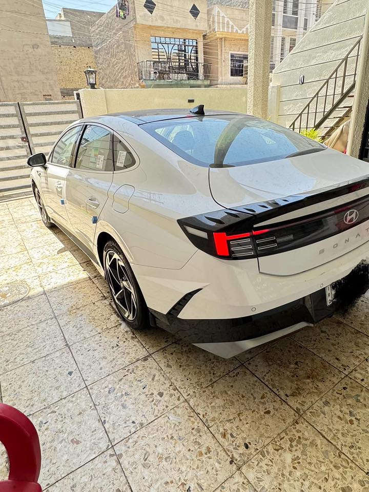 سوناتا 2024  ( خـليـجـي ) بعدها زيرو  بريحه الشركه  كفاله رقم بغداد بسمي عامه ماشيه 9000
الأداء والمحرك (المواصفات القياسية)
• المحرك: 4 أسطوانات (Smartstream) سعة 2.5 لتر.
• القوة الحصانية: حوالي 191 - 194 حصان.
• عزم الدوران: 245 نيوتن متر.
• ناقل الحركة: أوتوماتيكي بـ 8 سرعات.
• نظام الدفع: دفع أمامي (FWD).
• استهلاك الوقود: موفرة جداً، بمعدل تقريبي 16.3 كم/لتر (يختلف قليلاً حسب ظروف القيادة).
2. التصميم الخارجي
• الإضاءة: تتميز بشريط إضاءة LED ممتد في المقدمة يسمى "Seamless Horizon Lamp" يمنحها مظهراً مستقبلياً.
• المصابيح: مصابيح أمامية LED (نوع MFR) وإضاءة خلفية LED متصلة.
• الجنوط: تأتي بقياس 16 أو 17 بوصة من الألمنيوم في الفئة القياسية.
• المرايا: جانبية كهربائية مدمج بها إشارات انعطاف LED.
3. المقصورة والتقنيات الداخلية
• الشاشات: شاشة معلومات وترفيه تعمل باللمس مقاس 12.3 بوصة (أو 8 بوصة في بعض الأسواق لنسخ الفليت)، تدعم Apple CarPlay و Android Auto.
• لوحة العدادات: رقمية بسيطة مقاس 4.2 بوصة LCD تتوسط العدادات التقليدية.
• المقاعد: مكسوة بالقماش عالي الجودة مع تحكم يدوي أو كهربائي بسيط لمقعد السائق.
• التكييف: نظام تكييف هواء يدوي مع فتحات تهوية خلفية.
4. أنظمة السلامة والأمان (Standard)
تتميز سوناتا بأنها توفر حزمة أمان جيدة حتى في أقل فئة:
• وسائد هوائية أمامية مزدوجة (للسائق والراكب).
• نظام تثبيت السرعة (Cruise Control).
• حساسات ركن خلفية للمساعدة في الاصطفاف.
• نظام منع انغلاق المكابح (ABS) وتوزيع قوة الفرامل إلكترونياً (EBD).
• نظام مراقبة ضغط الإطارات (TPMS).
ماشيه9000km 
مكان السياره بغداد 
الاستفسار

‭0771 467 3844‬
