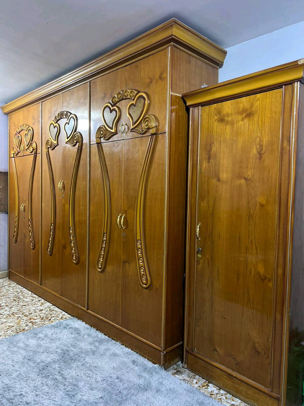 غرفة نوم خشبية أنيقة تتميز بالتصميم التقليدي والراقي مع نقوش قلبية جميلة على الخزانة والسرير. تحتوي على دولاب كبير مع مرايا أنيقة، بالإضافة إلى تسريحة مع مرآة واسعة تكمل جمال الغرفة. تُعد الغرفة مثالية لمن يحب الطراز الكلاسيكي وتناسب أي ديكور منزلي. حالة الخشب جيدة وتصميم الأثاث يضفي طابعاً مميزاً لأي غرفة نوم.