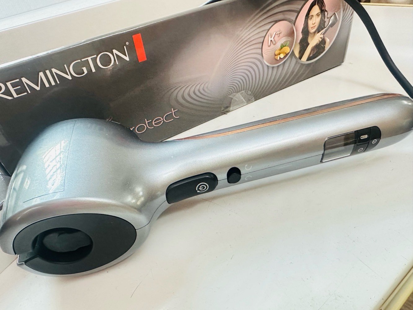 جهاز لف الشعر ، وهو جهاز مخصص لتمويج الشعر بشكل أوتوماتيكي دون الحاجة إلى لف الشعر يدويًا.

يعمل الجهاز عن طريق سحب خصلة الشعر تلقائيًا إلى داخل حجرة التسخين، حيث يتم تسخينها وتشكيلها على هيئة تموجات متناسقة خلال ثوانٍ، ثم يطلقها بشكل جاهز. هذه الآلية تجعل استخدامه سهلًا وآمنًا، خاصة لمن يجدن صعوبة في استعمال مكواة اللف التقليدية.

الجهاز مزوّد بطبقة سيراميكية متقدمة مدعّمة بالكيراتين وزيت اللوز (K+)، وهي تقنية تهدف إلى تقليل تلف الشعر الناتج عن الحرارة، مع الحفاظ على لمعانه ونعومته، مما يجعله مناسبًا للاستخدام المتكرر.

يوفر الجهاز عدة إعدادات لدرجة الحرارة تصل حتى 230 درجة مئوية، بحيث يمكن اختيار الدرجة المناسبة حسب نوع الشعر (ناعم، عادي، أو كثيف). كما يحتوي على خيارات متعددة لاتجاه التمويج (يمين، يسار، أو تلقائي) للحصول على مظهر طبيعي وغير متناسق بشكل مبالغ فيه