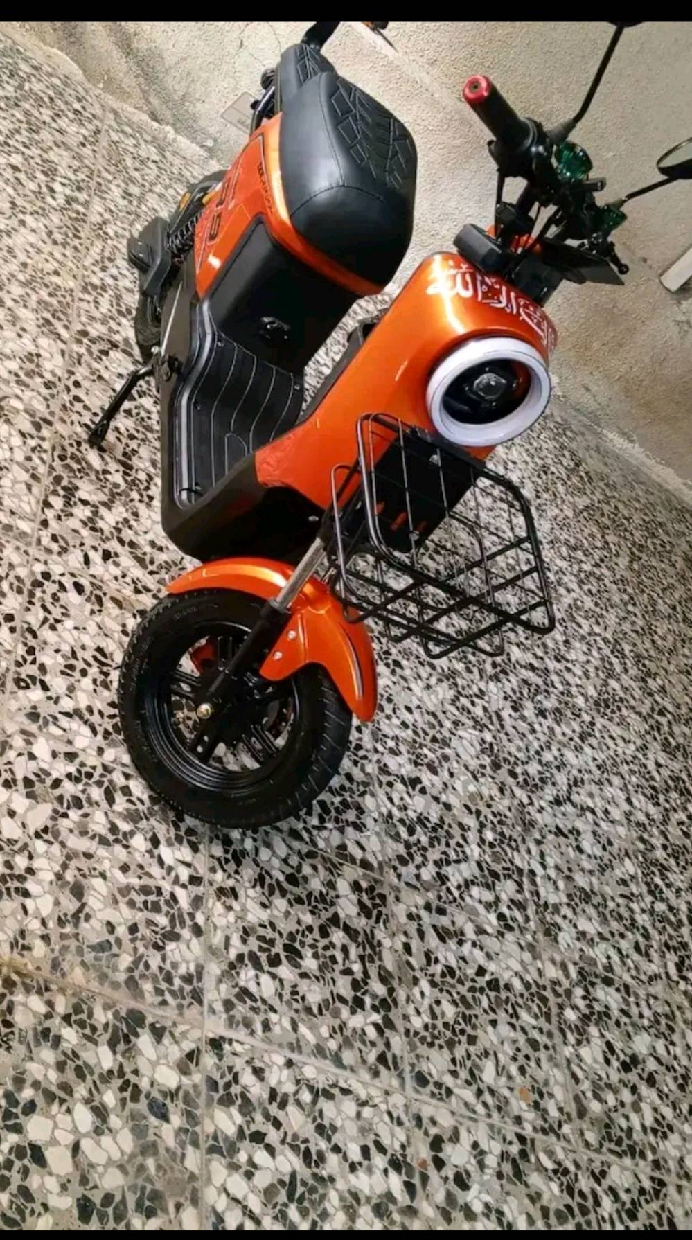 دراجة نارية كهربائية برتقالية بحالة ممتازة. تمتاز بسهولة القيادة وتوفير الوقود، مثالية للأستخدام اليومي في المدينة. الديكورات والإطارات في حالة جيدة، مع مقعد مريح وكبير يناسب جميع الأعمار.