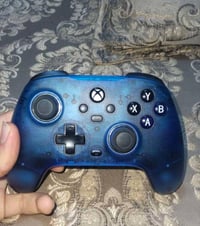 معروض للبيع جهاز Xbox مع يدين تحكم باللونين الأزرق والأزرق الغامق. الج...