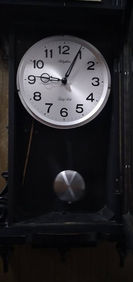 ساعة حائط بـ بندول (رقاص) من إنتاج شركة Rhythm اليابانية، وهي شركة عريقة معروفة بدقة محركاتها وتصاميمها الكلاسيكية.
​
​ هيكل الخارجي
​طراز: كلاسيكي مستوحى من طراز "منظم فيينا" (Vienna Regulator)، والذي يتميز بشكل طولي مع واجهة زجاجية تسمح برؤية البندول.
​اللون: الهيكل أسود المطفي مع لمسات تزيينية باللون الذهبي.
​ يوجد تمثال لحصان واثق، وهو عنصر تزييني تقليدي يمنح الساعة مظهراً فخماً.
​الأعمدة: على جانبي الساعة توجد أعمدة محفورة تعطي طابعاً معمارياً قديماً.
​النقوش: توجد زخارف نباتية (أزهار) في الجزء العلوي، وإكليل من الأوراق الذهبية على الزجاج السفلي يحيط بمجال حركة البندول.
​العلامة التجارية:  Rhythm   الموديل الذي يتميز بنغمات أو دقات معينة.
​ساعة بمحرك "كوارتز" (Quartz) دقيق.
​دق كل ساعة (أو نصف ساعة) بنغمات شهيرة مثل "Westminster


**إذا كنت صاحب هذا الإعلان وتريد حذفه لأي سبب، رجاءا أرسل رسالة إلى الدعم الفني**