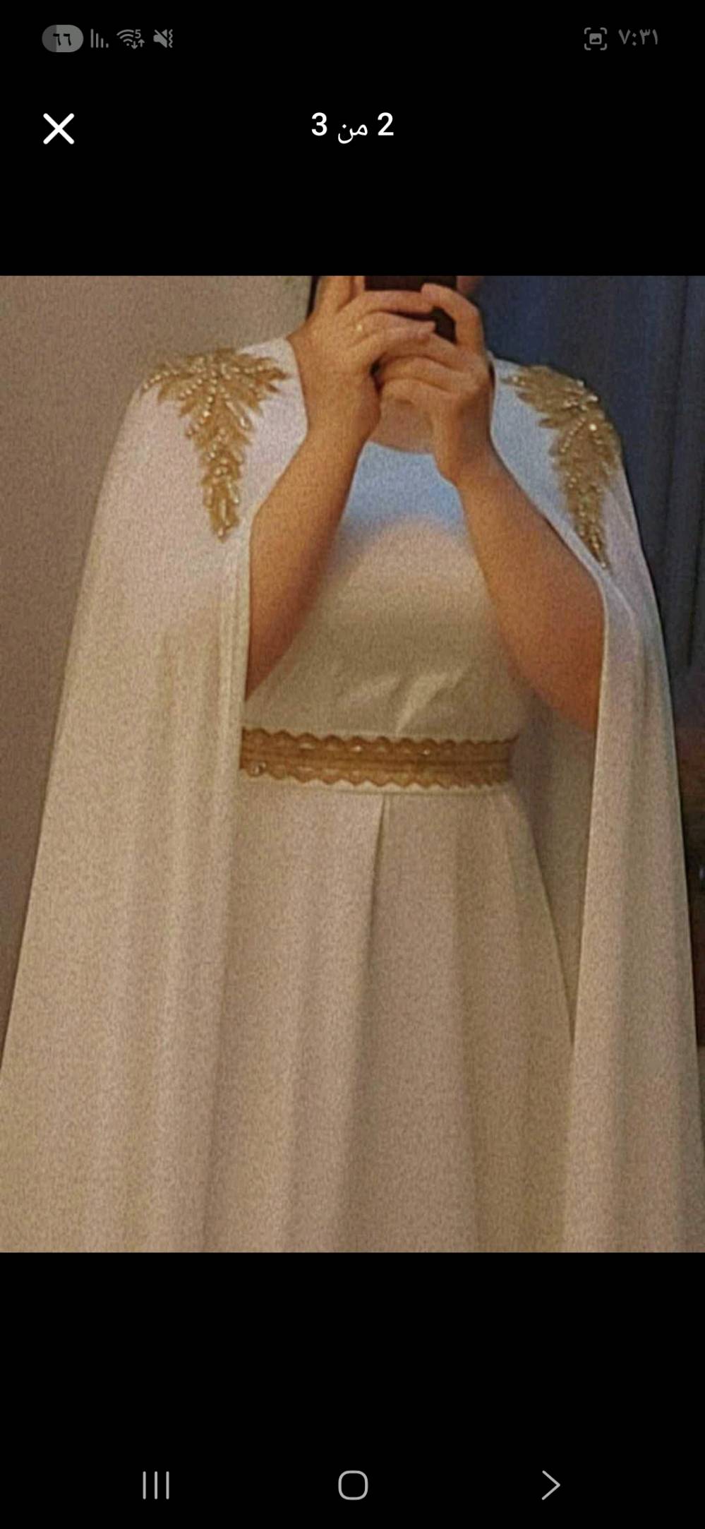  قفطان أبيض ملكي طويل، يتميز بتطريز يدوي ذهبي "شك خرز" على الأكتاف بأسلوب مستوحى من أوراق الشجر أو الأجنحة، مع شريط تطريز طولي في المنتصف.
  للمناسبات مثل الخطوبة 