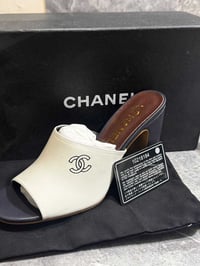 صندل مفتوح (Mule) أنيق من الجلد الأبيض يتميز بكعب عريض وشعار دار CHANE...