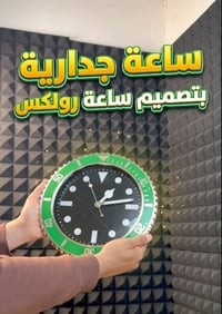 ساعة جدارية بتصميم أنيق يشبه ساعة رولكس. لها إطار دائري أخضر بأرقام وخ...