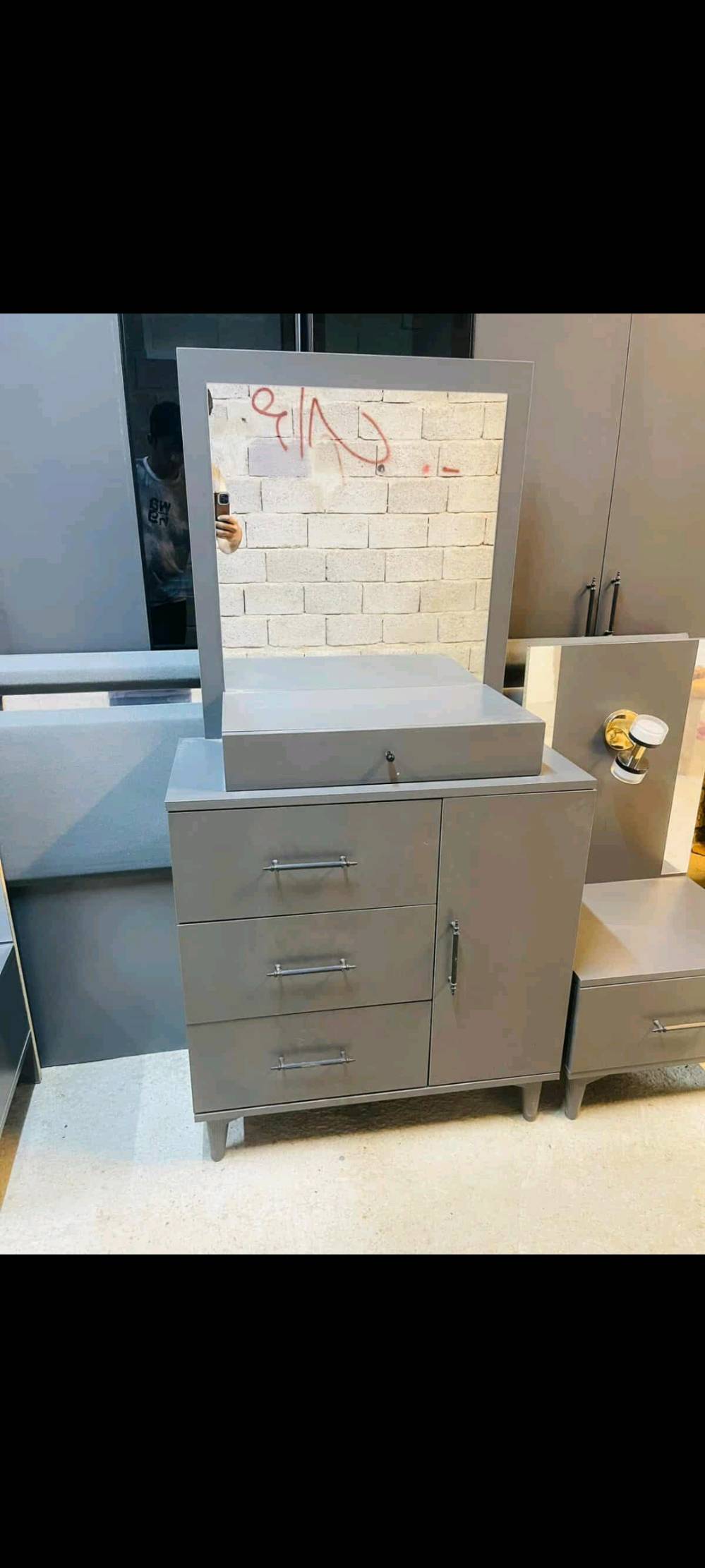 غرفة نوم متكاملة تتضمن خزانة ملابس واسعة بتصميم عصري مع أبواب زجاجية، ودرج بحجم مناسب للتخزين، وتسريحة مع مرآة مميزة. التصميم بسيط وأنيق باللون الرمادي مما يجعله ملائم لجميع الديكورات الداخلية. صنع بدقة عالية لضمان المتانة والجودة.