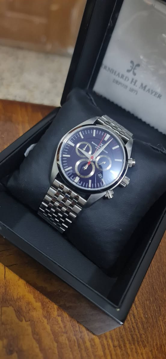 بناءً على الصورة، هذه الساعة هي من العلامة التجارية السويسرية Bernhard H. Mayer، وتحديداً موديل Ascent Chronograph (أو طراز مشابه جداً من مجموعة الكرونوغراف الكلاسيكية لديهم).
​إليك أهم مواصفاتها التقنية المعتادة لهذا الإصدار:
​المواصفات العامة:
• ​بلد المنشأ: سويسرية الصنع (Swiss Made).
• ​الهيكل (Case): مصنوع من الفولاذ المقاوم للصدأ (Stainless Steel 316L) المصقول والناعم.
• ​المينا (Dial): باللون الأزرق الداكن مع مؤشرات مضيئة (Luminescent) للساعة والدقائق.
• ​الزجاج (Crystal): زجاج ياقوت (Sapphire Crystal) مقاوم للخدش مع طبقة مضادة للانعكاس.
• ​السوار (Bracelet): سوار من المعدن (Stainless Steel) بتصميم خماسي الحلقات (أشبه بتصميم Jubilee) مع مشبك قابل للطي.
​الوظائف (Functions):
• ​نظام الحركة (Movement): كوارتز سويسري (Swiss Quartz)، وغالباً ما تستخدم هذه العلامة ماكينات Ronda.
• ​الكرونوغراف (Chronograph): تحتوي على ثلاث عدادات فرعية لقياس الثواني، الدقائق، والساعات (أو أجزاء من الثانية حسب الموديل الدقيق).
• ​التاريخ (Date): نافذة لعرض التاريخ تقع عادةً عند الساعة الرابعة أو السادسة (في صورتك تظهر عند الساعة الرابعة تقريباً).
• ​مقاومة الماء: غالباً ما تكون مقاومة للماء حتى عمق 50 أو 100 متر (5 - 10 ATM)، مما يجعلها مناسبة للاستخدام اليومي والسباحة السطحية.
​ملاحظات إضافية:.
• ​يتميز هذا الموديل بالعقرب الأحمر النحيف للثواني (الخاص بالكرونوغراف) الذي يعطي لمسة رياضية للمينا الأزرق.
​السعر ٨٥٠ الف وبيها مجال بسيط


**إذا كنت صاحب هذا الإعلان وتريد حذفه لأي سبب، رجاءا أرسل رسالة إلى الدعم الفني**