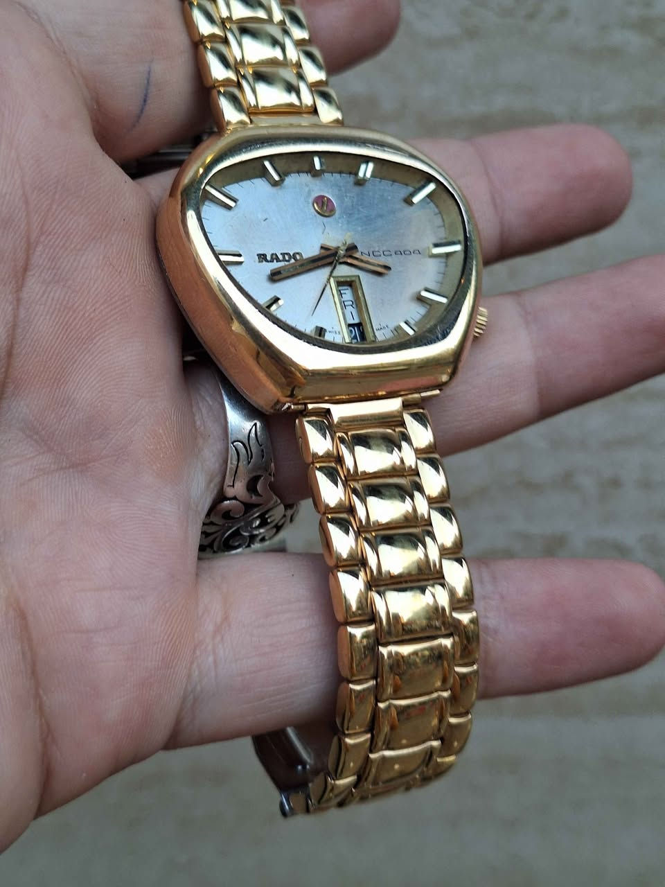 ساعة Rado NCC 404 السويسرية الكلاسيكية، والمعروفة بين الهواة والمجمعين باسم "Rado Cobra" نظراً لشكل هيكلها الفريد غير المتماثل الذي يشبه رأس أفعى الكوبرا.تنتمي هذه الساعة إلى سلسلة "NCC" (اختصار لـ New Case Concept) التي أطلقتها شركة رادو السويسرية في أواخر الستينيات وبداية السبعينيات لتجربة تصاميم وهياكل هندسية مبتكرة ومقاومة للصدمات والماء بشكل متطور في وقتها.أبرز مواصفات ومميزات الساعة:التصميم والهيكل: تأتي بهيكل فريد ومطلي بالذهب. يتميز التصميم بغياب العروات التقليدية (Lugs) مما يجعلها مريحة جداً على المعصم رغم حجمها البارز.المينا (Dial): باللون الفضي/الذهبي الفاتح مع مؤشرات بارزة ثلاثية الأبعاد (Baton Indices) وعقارب ذهبية متناسقة.نافذة التاريخ: تتميز بنافذة رأسية فريدة لعرض اليوم والتاريخ معاً عند مؤشر الساعة 6.شعار المرساة (Anchor Logo): يتوسط المينا تحت مؤشر الساعة 12 شعار رادو الشهير "المرساة المتحركة".الحركة: تعمل بحركة ميكانيكية أوتوماتيكية (سويسرية الصنع) معتمدة على الاهتزاز والتحرك الذاتي. مركز طوخ, القليوبية


**إذا كنت صاحب هذا الإعلان وتريد حذفه لأي سبب، رجاءا أرسل رسالة إلى الدعم الفني**