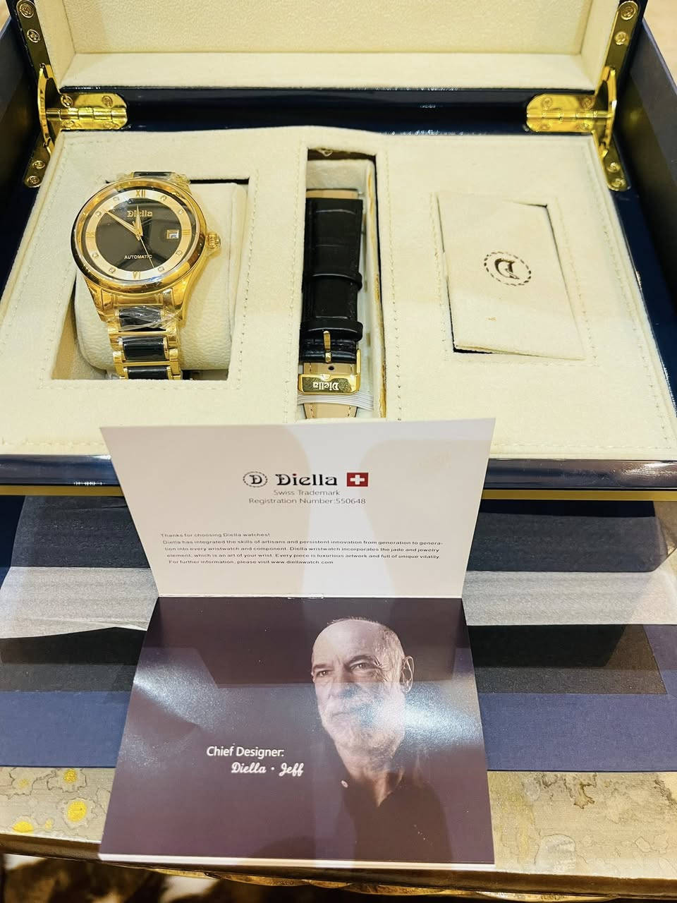 قطعه تحفه ساعه من ماركة Diella، وتحديداً موديل AD6008. تتميز هذه الساعة بتصميم فاخر يجمع بين الذهب واليشم (Jade) الأسود أو الأخضر الداكن، وهي ساعة أوتوماتيكية ميكانيكية لا تحتاج إلى بطارية. 
أبرز مواصفات الساعة:
الحركة: ميكانيكية أوتوماتيكية تعتمد على حركة المعصم لتوليد الطاقة.
المواد: مصنوعة من الفولاذ المقاوم للصدأ المطلي باللون الذهبي مع ترصيع باليشم الطبيعي في السوار والإطار.
المينا: يحتوي على أحجار الراين كعلامات للساعات، مع نافذة لعرض التاريخ عند الساعة الثالثة.
المقاومة للماء: مقاومة للماء حتى عمق 50 متراً (5ATM)، مما يجعلها مناسبة للاستخدام اليومي مثل غسل اليدين أو التعرض للمطر.
الزجاج: مرآة من زجاج الياقوت (Sapphire Glass) المقاوم للخدش. 
تأتي الساعة عادةً في صندوق فخم مع سوار إضافي من الجلد وأداة لتعديل طول السوار المعدني.


**إذا كنت صاحب هذا الإعلان وتريد حذفه لأي سبب، رجاءا أرسل رسالة إلى الدعم الفني**