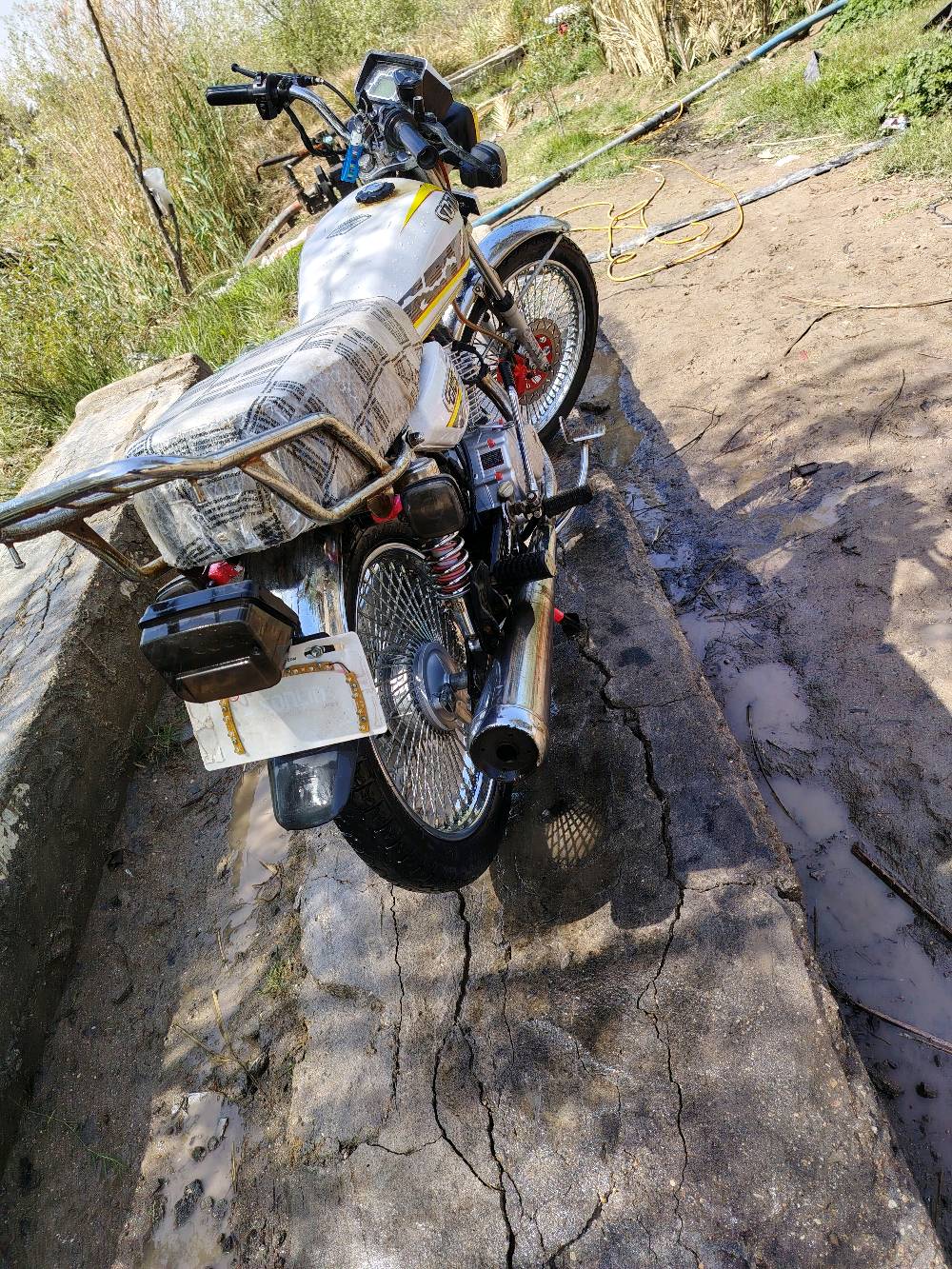 دراجة نارية نوع دايون CG125 بحالة ممتازة، لونها أبيض مع رسومات جانبية. الدراجة نظيفة ومجهزة بالكامل، مما يجعلها مثالية للاستخدام اليومي أو المشاوير الطويلة.