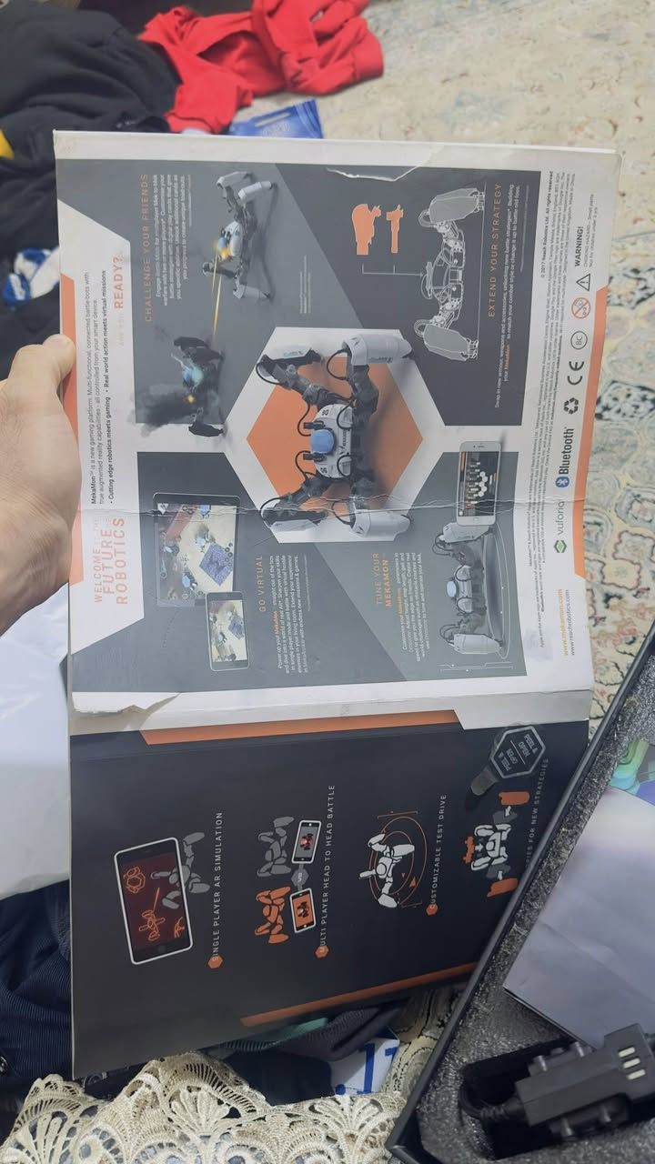 ميكامون)، وهو روبوت متطور يدمج بين العالم الحقيقي والواقع المعزز (AR)، من إنتاج شركة Reach Robotics. هو ليس مجرد لعبة عادية، بل يعتبر "روبوت قتال" ذكي.
إليك أهم مواصفاته ومميزاته بناءً على ما يظهر في الصور:
1. طريقة اللعب
• الواقع المعزز (AR): يمكنك استخدام هاتفك لرؤية أعداء افتراضيين في غرفتك ومحاربتهم باستخدام الروبوت.
• قتال الروبوتات: إذا كان لدى صديقك روبوت آخر، يمكنكما القتال وجهاً لوجه في عالم حقيقي.
• التحكم: يتم التحكم به بالكامل عبر تطبيق على الهاتف الذكي (iOS أو Android).
2. المواصفات التقنية (كما في المخطط بالصورة الأولى)
• التصميم: يمتلك 4 أرجل تتحرك بمرونة عالية (ثلاث درجات من الحرية لكل رجل)، مما يسمح له بالمشي، الدوران، وحتى أداء حركات تعبيرية.
• الهيكل (Chassis): مصنوع من مواد قوية وخفيفة الوزن لتحمل الصدمات أثناء القتال.
• الدروع والأسلحة: يتميز بنظام "الوحدات" (Modular)، أي يمكنك نزع وتركيب الدروع والأسلحة (المستشعرات) لتغيير قدراته.
• المستشعرات: مزود بمستشعرات تحت حمراء (Infrared) لاكتشاف الروبوتات الأخرى وتحديد الإصابات.
3. مميزات إضافية
• التخصيص: يمكنك ترقية مستوى الروبوت الخاص بك وفتح قدرات جديدة من خلال التطبيق.
• الحركة: يتميز بحركة "عضوية" تشبه الكائنات الحية،


**إذا كنت صاحب هذا الإعلان وتريد حذفه لأي سبب، رجاءا أرسل رسالة إلى الدعم الفني**