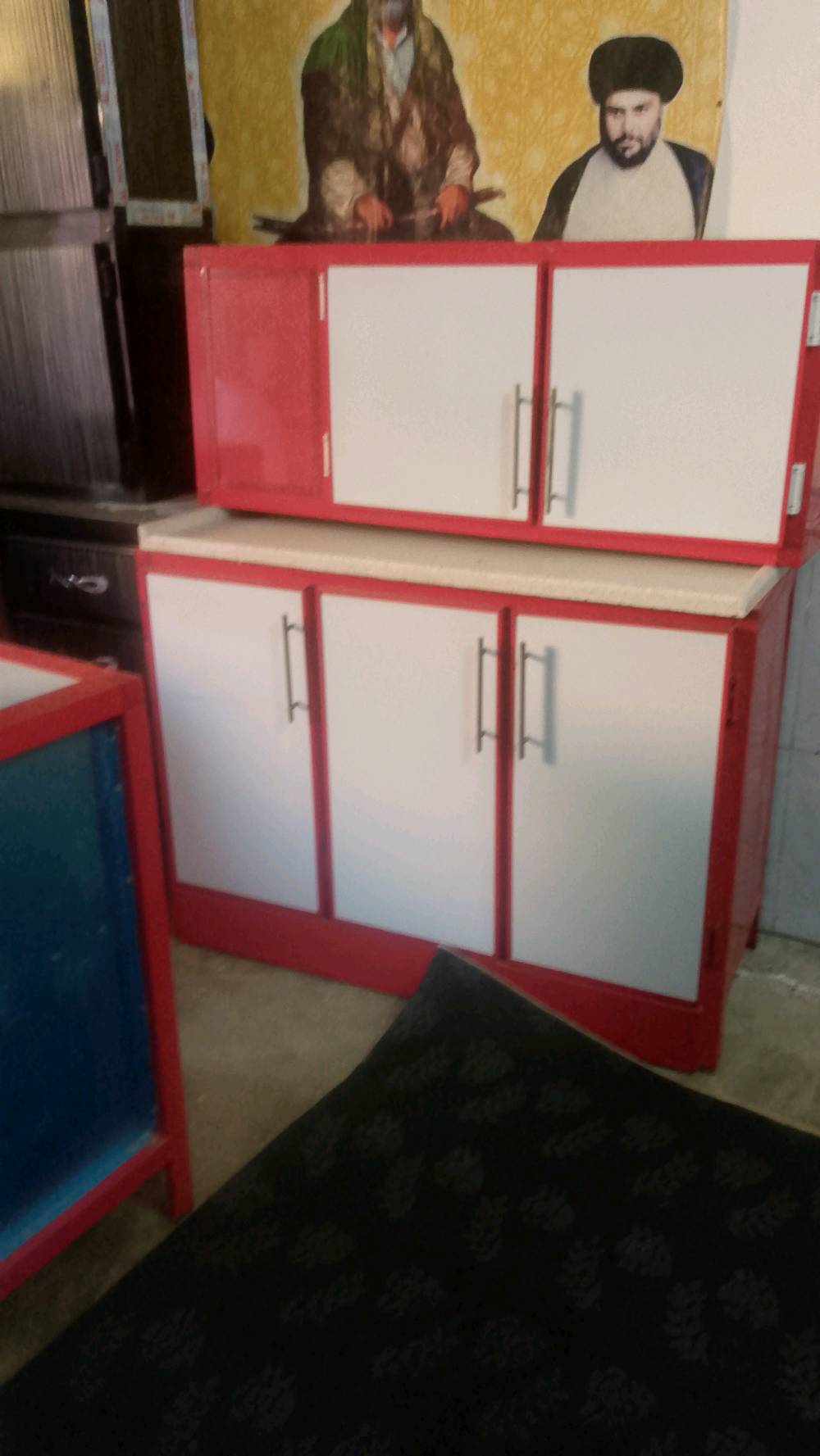 كاونتر مطبخ بلونين أحمر وأبيض، مثالي لترتيب المطبخ وتخزين الأدوات والأواني. يتميز بتصميمه العصري الجميل ويتضمن مقابض فضية لسهولة الفتح والاغلاق. مناسب للمطابخ الحديثة ويضيف لمسة جمالية للمكان.