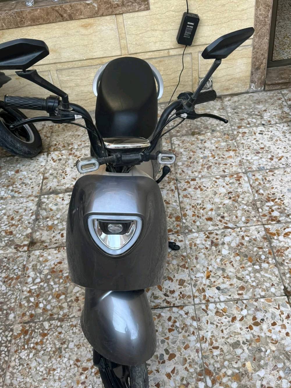 دراجة كهربائية أنيقة باللون الرمادي، مثالية للتنقل السريع والسهل داخل المدينة. تتميز بتصميم مريح وعصري مع مصابيح أمامية قوية لزيادة الأمان أثناء القيادة في الليل. تم استخدام الدراجة بحالة ممتازة وتعمل بكفاءة عالية.