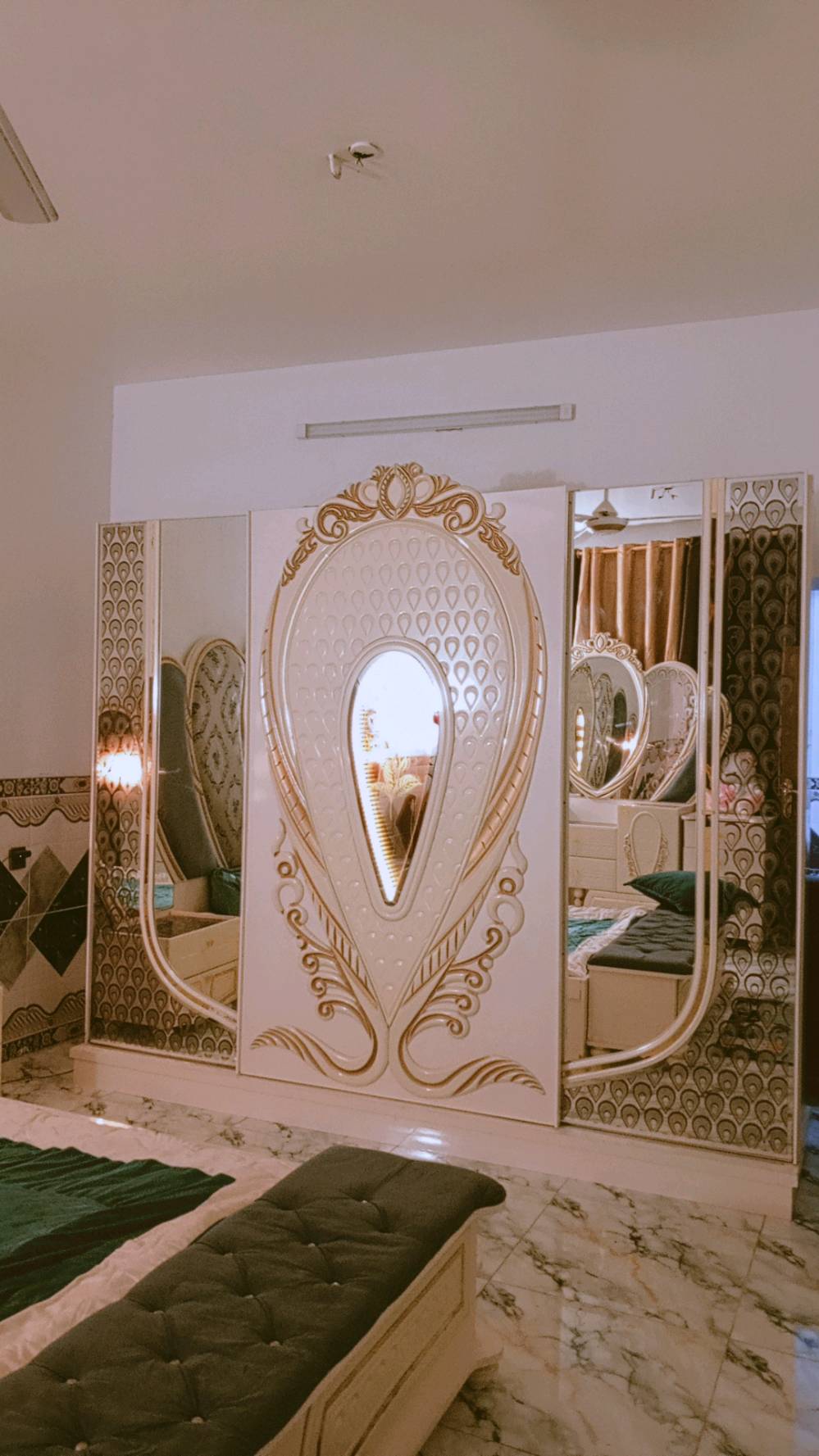 غرفة نوم مميزة بتصميم كلاسيكي فاخر، تتكون من سرير كبير ومريح مع لوح رأس ذو زخارف أنيقة ومرآة رائعة. الطقم يشمل أيضًا خزائن جانبية وتصميم فني على الجدران والخزائن. القطع مصنوعة بعناية لتضيف لمسة من الفخامة لأي غرفة نوم.