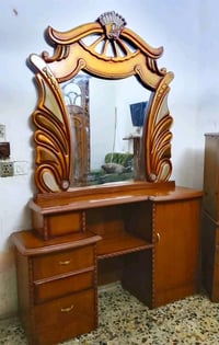 غرفة نوم تتكون من سرير مريح مع مسند خشبي مزخرف، وتسريحة مع مرآة كبيرة ...