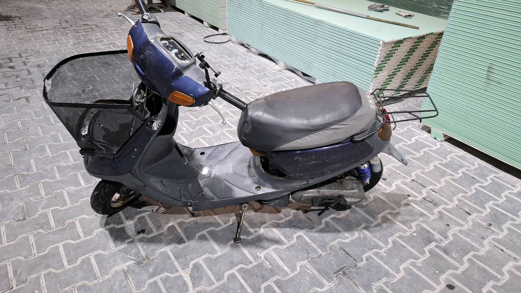 دراجة نارية سكوتر مستخدمة، لونها أزرق وغامقة، مناسبة للتنقلات اليومية داخل المدينة. تحتاج إلى بعض الصيانة في الجزء الأمامي ولكن بشكل عام حالة جيدة.

**الموقع:** بغداد