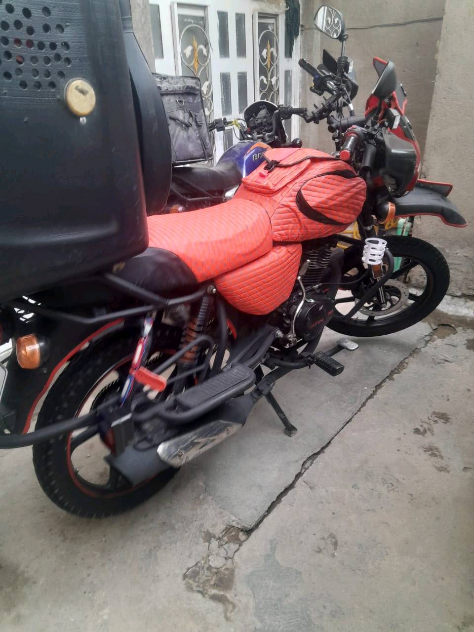 درّاجة نارية نوع دايون مع غطاء برتقالي خاص للتنجيد لمحافظة على المقاعد. بحالة ممتازة، مثالية للتنقل داخل المدينة والرحلات اليومية. العداد يظهر 23666 كيلومتر. متوفرة في بغداد وجاهزة للاستخدام المباشر.