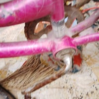 دراجة هوائية بلون وردي مناسبة للأطفال، فيها زينة ملونة على العجلات. تح...