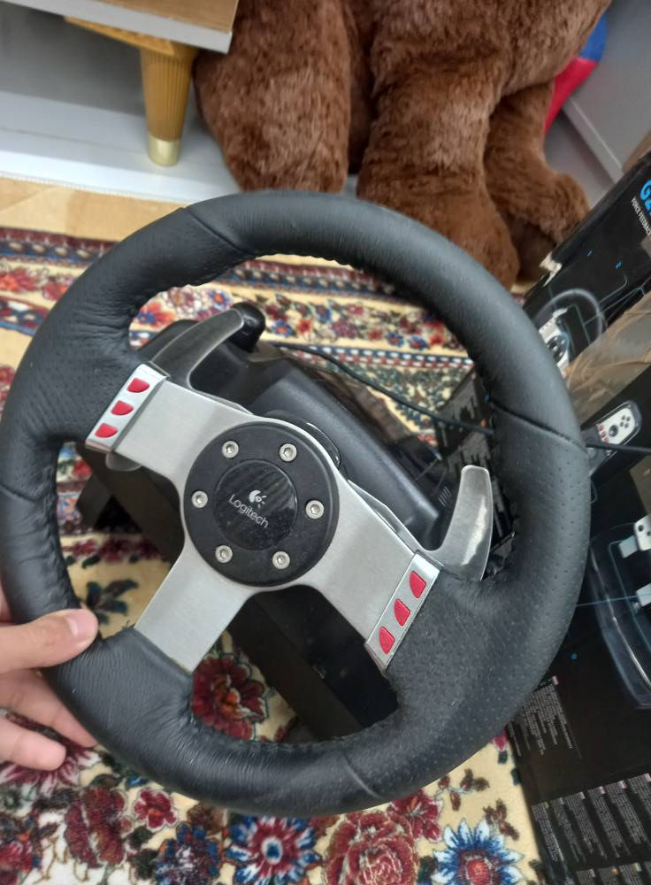لحد 900 درجة مثل السيارة الحقيقية �
Wikipedia +1
⚙️ Force Feedback:
يحتوي على محركين Dual-Motor حتى تحس بالطريق والاهتزاز والتفحيط بشكل واقعي �
HEXUS.net +1
🔇 نوع التروس:
Helical Gears
يعني صوت أنعم وأهدأ من G25 �
Wikipedia +1
🛞 الدركسون:
مقاس 27 سم تقريبًا
جلد حقيقي (Leather Wrapped) �
Wikipedia +1
🦶 البدالات:
3 بدالات:
بنزين
بريك
كلتش
ومصنوعة من الستانلس ستيل �
Wikipedia +1
🕹️ القير:
قير يدوي H-Pattern
6 سرعات + ريوس (Reverse) �
Wikipedia +1
🎯 أزرار:
أزرار على الدركسون والقير
Paddle Shifters خلف الدركسون �
Wikipedia
🔌 التوصيل:
USB + محول كهرباء خارجي بغداد, العراق


**إذا كنت صاحب هذا الإعلان وتريد حذفه لأي سبب، رجاءا أرسل رسالة إلى الدعم الفني**