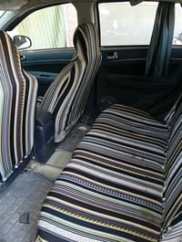 سيارة بيضاء بحالة جيدة، فيها مقاعد مغطاة بحماية وديكورات داخلية بسيطة....