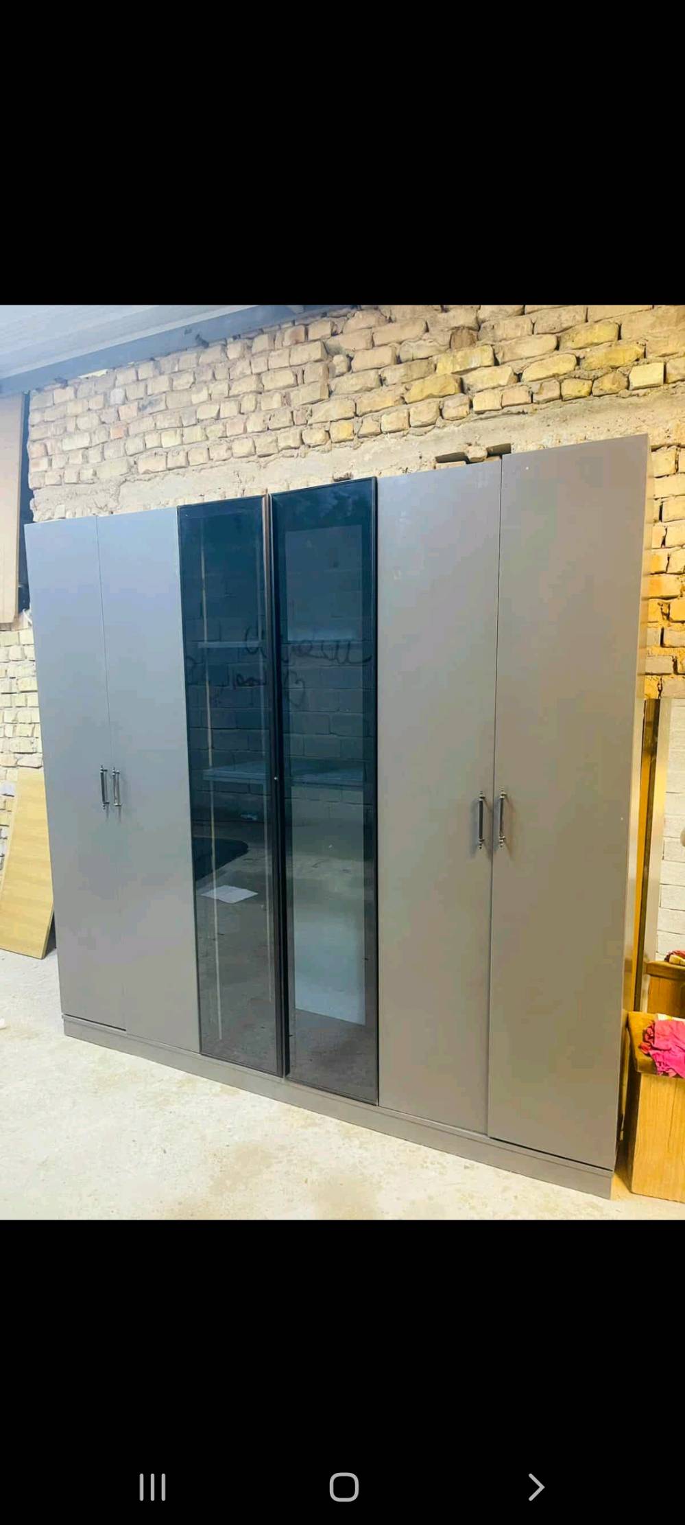 غرفة نوم متكاملة تتضمن خزانة ملابس واسعة بتصميم عصري مع أبواب زجاجية، ودرج بحجم مناسب للتخزين، وتسريحة مع مرآة مميزة. التصميم بسيط وأنيق باللون الرمادي مما يجعله ملائم لجميع الديكورات الداخلية. صنع بدقة عالية لضمان المتانة والجودة.