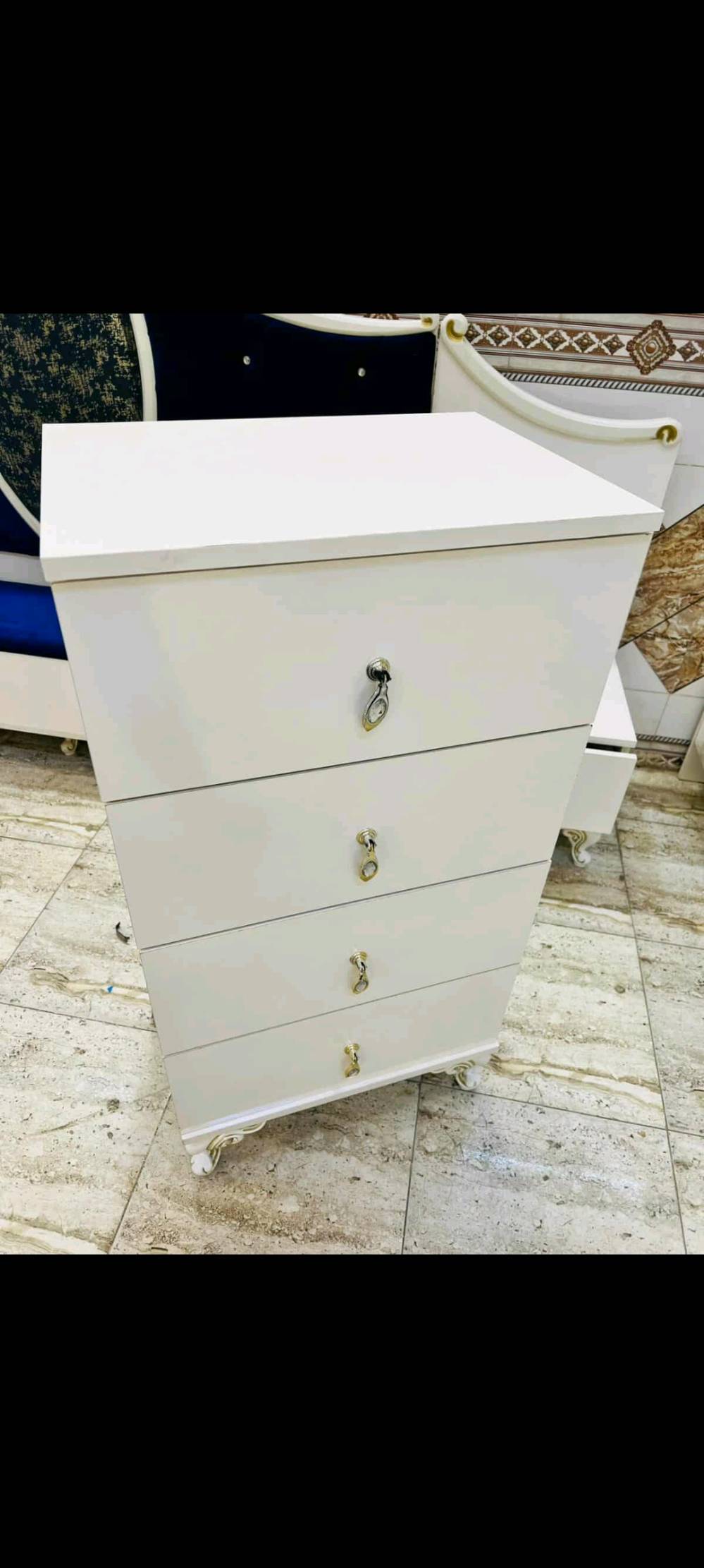 غرفة نوم فاخرة بتصميم كلاسيكي تشمل سرير مريح مع لوح أمامي مبطن باللون الأزرق الداكن وخزانة ملابس كبيرة مع مرايا زخرفية. تتميز الغرفة بتفاصيل ذهبية على الأبواب والأدراج، مما يضفي لمسة من الفخامة والرقي. الطقم يشمل أيضًا تسريحة مع مرآة كبيرة وكرسي مبطن لتوفير الراحة أثناء التحضير اليومي. الأثاث مصنوع بجودة عالية ويضفي لمسة فنية على أي غرفة نوم.