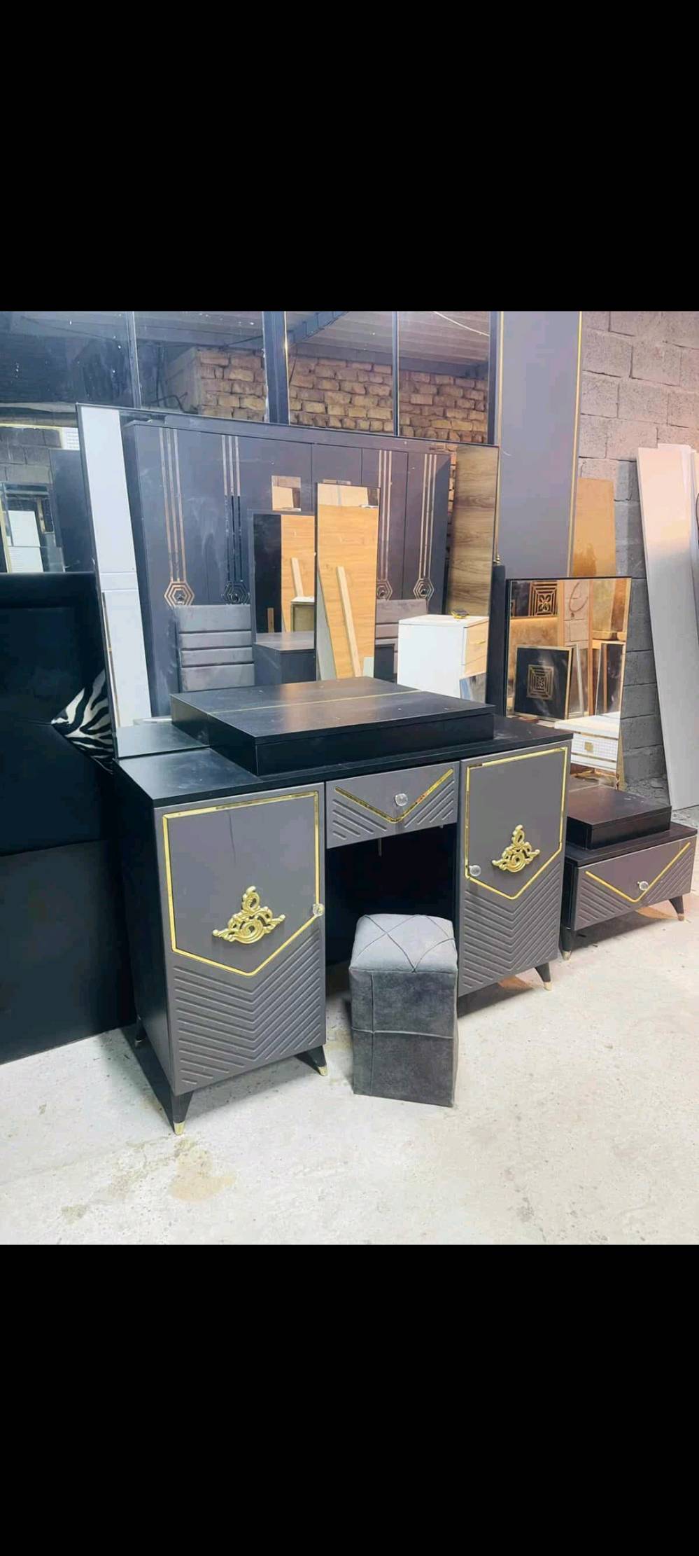 شروط جديدة مودرن، غرفة نوم متكاملة تظم سرير بتنجيد مميز، دولاب ملابس أنيق بمرايا تغطي الأبواب، وتواليت متعدد الأدراج. تفاصيل الحفر الذهبي تضيف لمسة من الفخامة، مما يجعلها خياراً مثالياً للمنازل الحديثة والمتجددة.