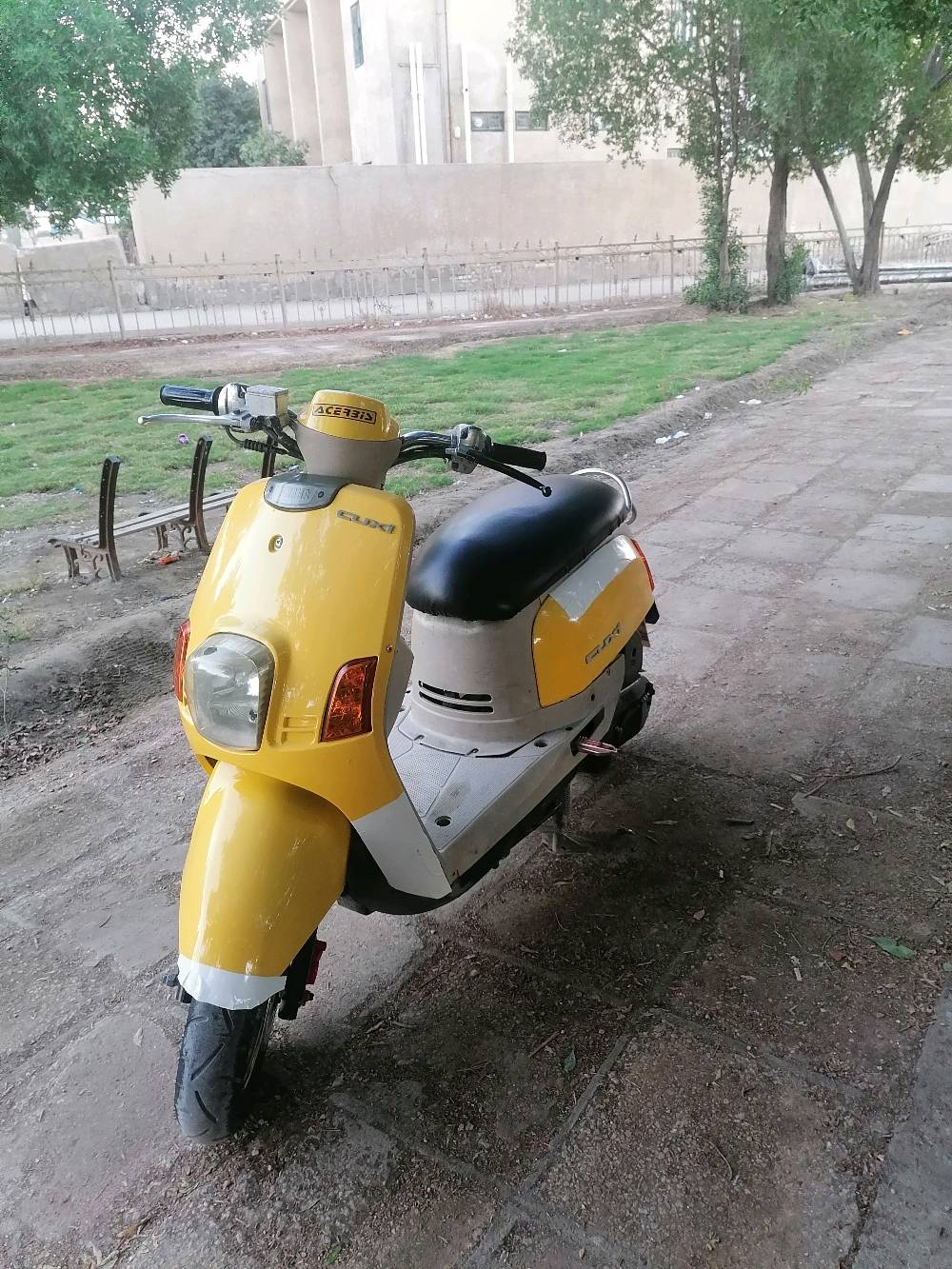 دراجة نارية نوع سكوتر لون أصفر. بحالة جيدة ومريحة للاستخدام اليومي داخل المدينة. مناسبة للتنقل السريع والاقتصادي. قليل المسافة المستهلكة نظرًا لاقتصادها في استهلاك الوقود. محرك قوي وسهل الاستخدام.