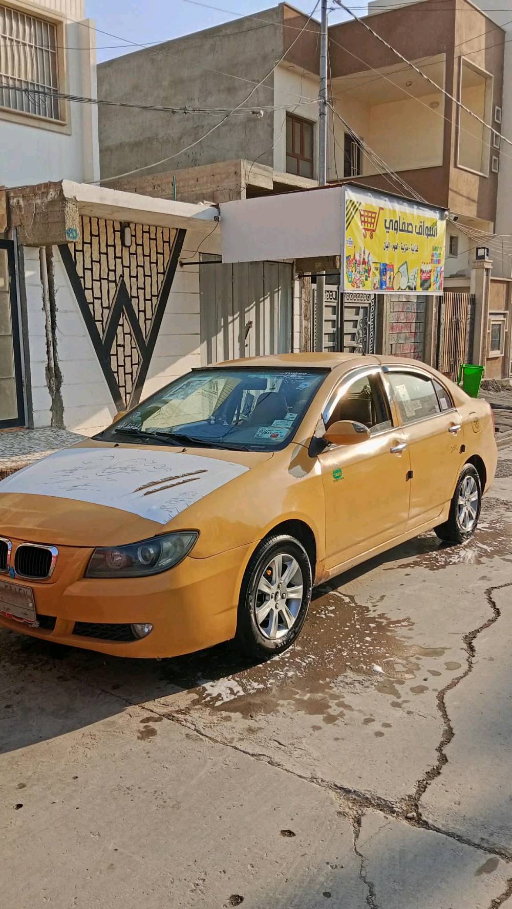 سيارة صالون لون أصفر مع ملامح بارزة واضحة، تشمل سقف وجوانب بتزيين. الداخلية نظيفة ومعتنى بها مع لوحة قيادة تعرض تصميمًا حديثًا وداخلية مريحة. السيارة مثالية للاستخدام اليومي أو كتاكسي، وتتميز بمساحة داخلية مريحة ومظهر خارجي متين.