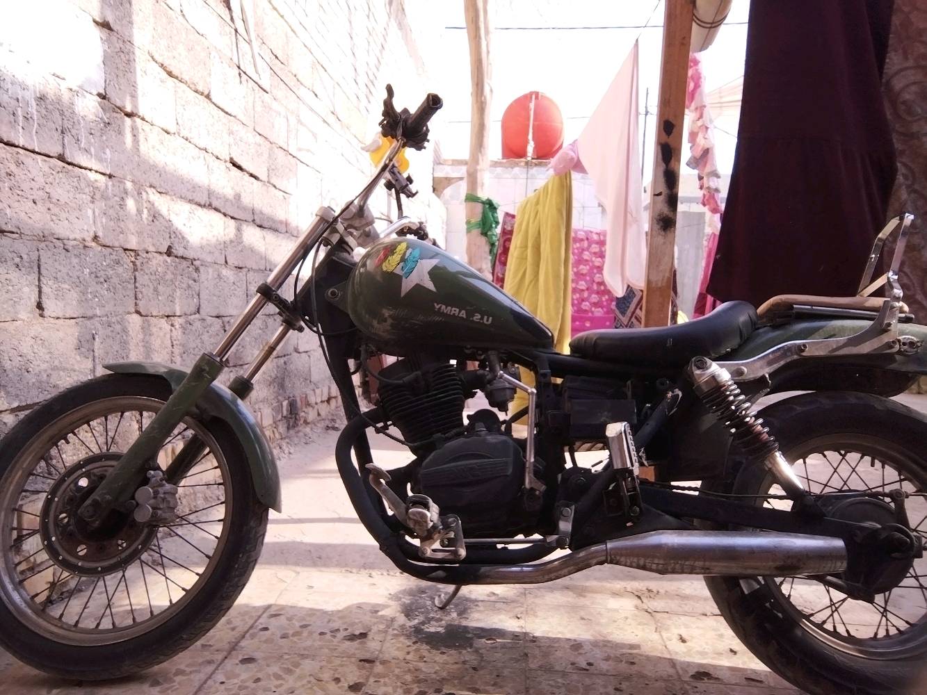 دراجة نارية عسكرية قديمة من نوع ياماها، لونها أخضر غامق مع رسومات مميزة تضيف لمسة كلاسيكية. مناسبة لعشاق الدراجات الكلاسيكية والمغامرات. تعمل بكفاءة ودون مشاكل، وجاهزة للمغامرة القادمة.