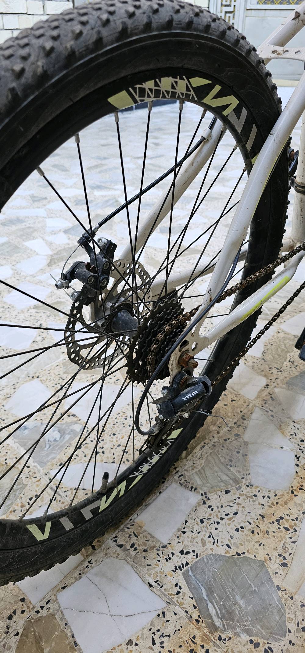 باسكل جبلي بحالة جيدة. اللون أبيض مع تفاصيل سوداء، يمتاز بإطارات عريضة للتضاريس الصعبة. مناسب لجولات الطرق الوعرة وقيادة مريحة في المناطق الجبلية.