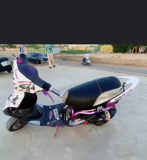 دراجة سكوتر مميزة ومعدلة بلون أسود وبنفسيجي مع تفاصيل إضافية وملصقات. مناسبة للتنقل اليومي وتمنحك تجربة ممتعة ومريحة. بحالة جيدة وجاهزة للاستخدام الفوري.