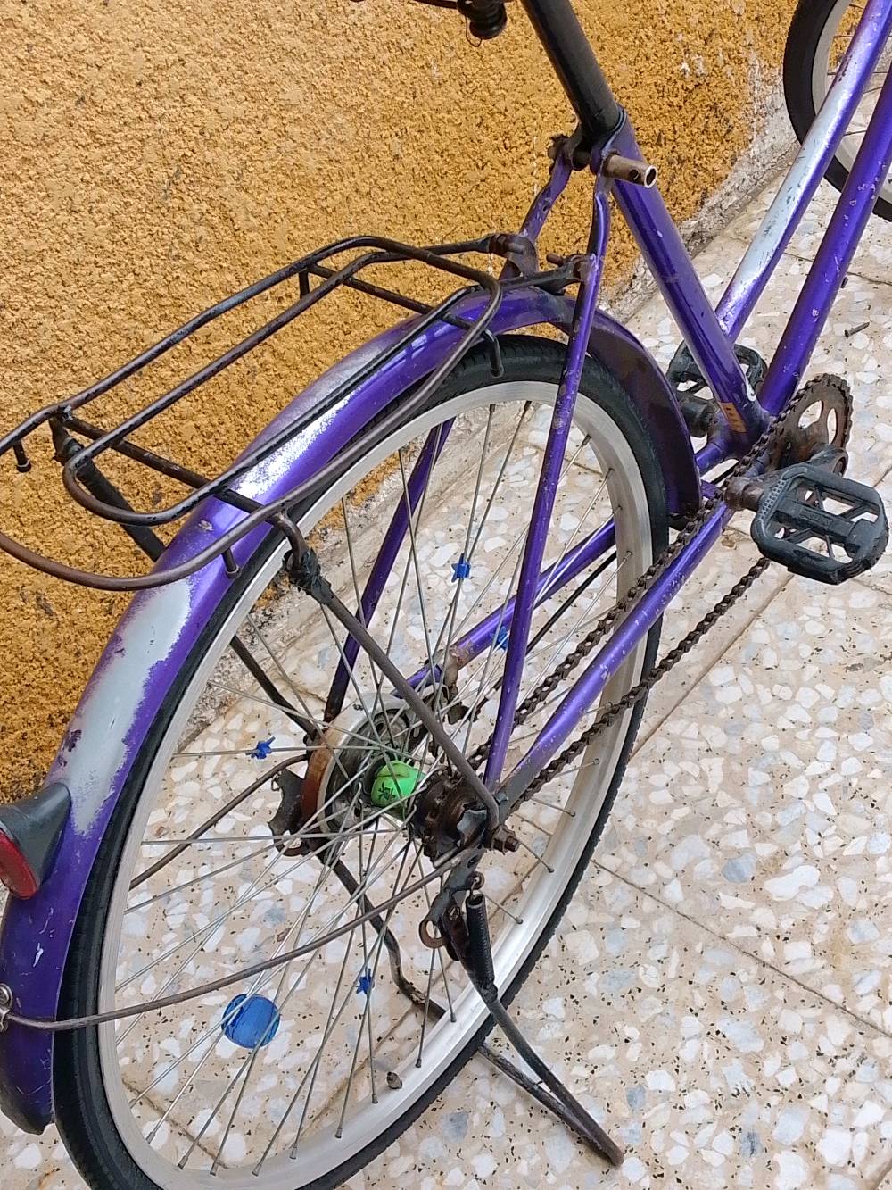 درّاجة هوائية بلون بنفسجي بحالة جيدة كما تظهر في الصور، مثالية للتنقل اليومي في المدينة. فيها رف خلفي لحمل الأغراض. تحتاج إلى بعض التعديلات البسيطة على الجنزير والفرامل. السعر معقول ومنافس للسوق، ولا يشمل الاكسسوارات.