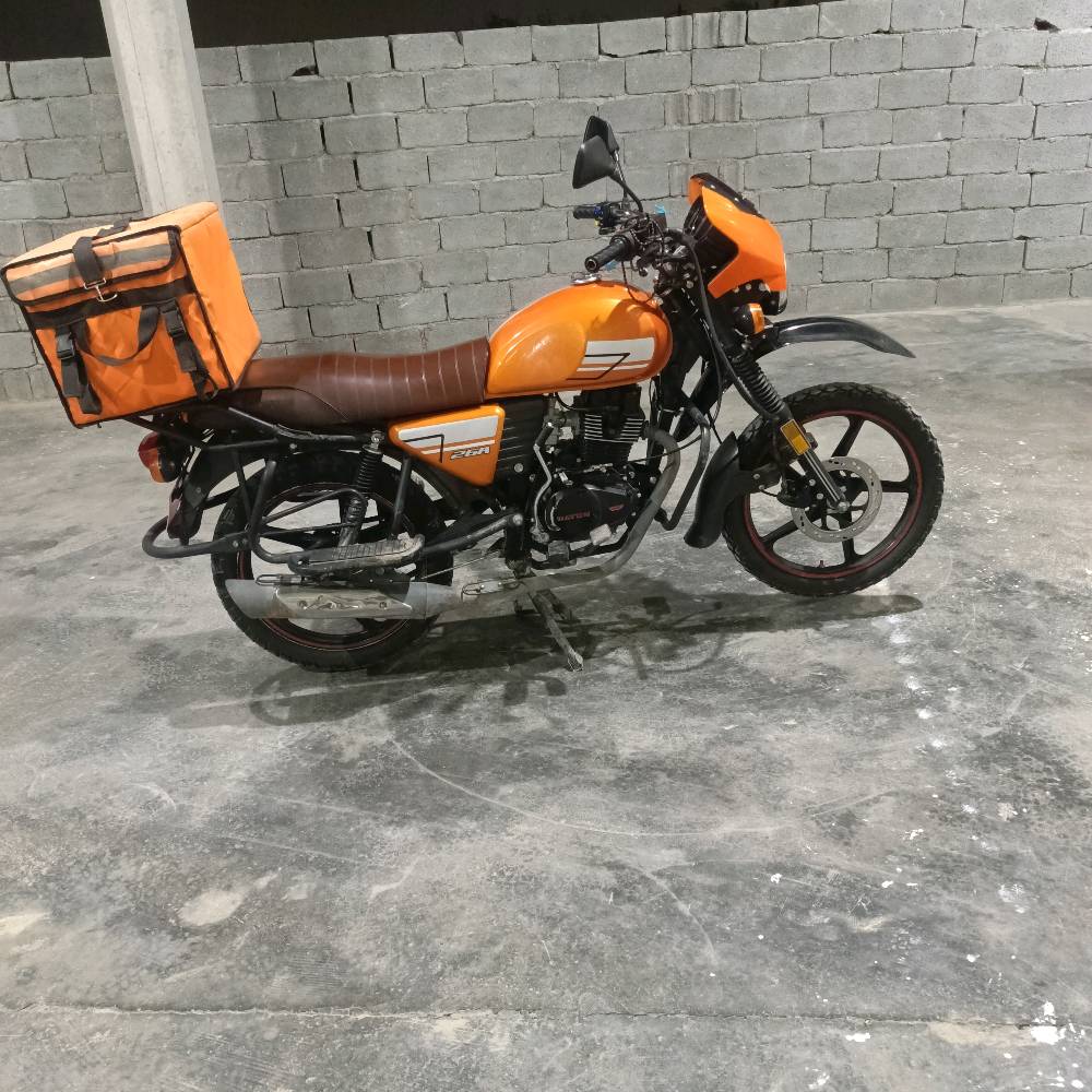 دراجة نارية برتقالية اللون بحالة جيدة جداً، مثالية للاستخدام اليومي والتنقل. تحتوي على حقيبة تخزين خلفية كبيرة، ممتازة لتوصيل الطرود أو استخدامات المتعددة. تمتاز بمقعد مريح وتصميم عصري. السعر منافس ومناسب لمن يبحث عن أداء عالي بأسعار معقولة.