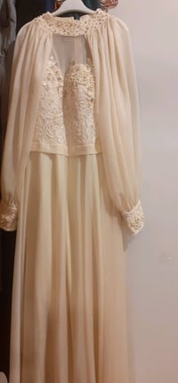 فستان سهرة أنيق مزين بالدانتيل والخرز، باللون البيج. يتميز بتصميمه الف...