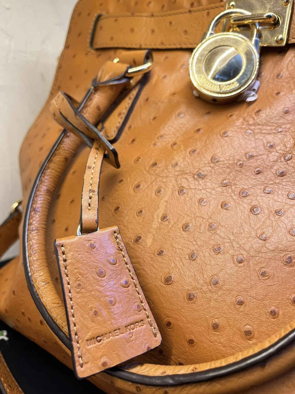 حقيبة اليد هذه هي حقيبة يد (توت) هاميلتون من مايكل كورس بنقشة النعام البارزة. تتميز الحقيبة بلونها البرتقالي المائل للسمرة وتفاصيلها الذهبية، بما في ذلك القفل المتدلي وحزام السلسلة الاختياري. 

العلامة التجارية: مايكل كورس (Michael Kors)
الموديل: هاميلتون (Hamilton)
الخامة: جلد بنقشة النعام البارزة
اللون: برتقالي أو تان (Orange/Tan)
الميزات: قفل ذهبي مميز، ومقابض علوية، وحزام كتف سلسلة اختياري
الحالة: مستخدمة استعمال خفيف – نظيفة وبحالة جيدة
• المناسبة: يومي، دوام، مناسبات خفيفة، سفر
• السعة: متوسطة – تشيل أغراض أساسية (محفظة، موبايل، مفاتيح، عطر)
للتواصل خاص : *********** فقط واتساب
