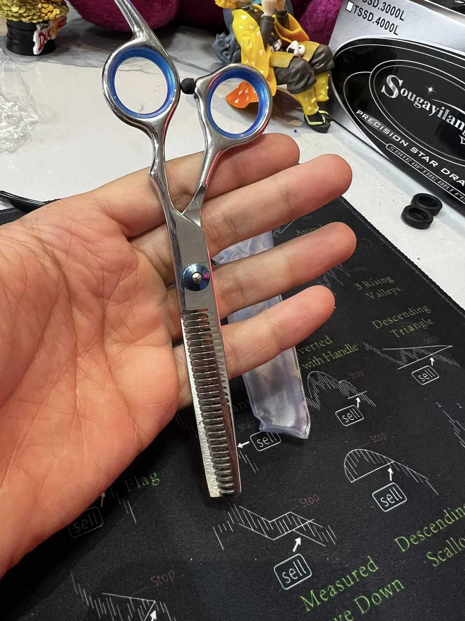 مقص حلاقة  (Straight Scissors): هذا المقص الأساسي، حاد ومصمم حتى يكص الشعر بدقة. بي "ساندة" للأصبع حتى تسيطر عليه وما يتعب إيدك.
• مقص تشفير (Thinning Scissors): هذا المقص اللي بي سنون (مثل المشط). وظيفته يقلل كثافة الشعر (يخففه) بدون ما يكصر طوله، ويستخدموه حتى يدمجون طبقات الشعر ويطلع الموديل مرتب.
• مشط حلاقة: مشط أسود كلاسيكي، جهة سنونها ناعمة وجهة خشنة، ضروري ويه الكص.
• ماشة (قرصات) شعر: ذني السود الثنين، يفيدنك حتى تعزل الشعر وتكص جزء جزء براحتك.
• وصلة تنظيف: قطعة قماش (لونها خردلي) ناعمة حتى تمسح بيها المقصات من الدهن أو بقايا الشعر وره ما تخلص.
• محفظة (قلمية): الجنطة السودة الصغيرة اللي تلم الغراض كلهن حتى لا يضيعن ولا يتثلم المقص.
ليش هذا السيت زين؟
1. الديزاين: المقصات بيها حلقات زرقة داخلية، هاي مطاطية (ربر) حتى لا تزلق أصابعك وتكون مريحة بالشغل.

السعر 65.000

الحجز ***********
